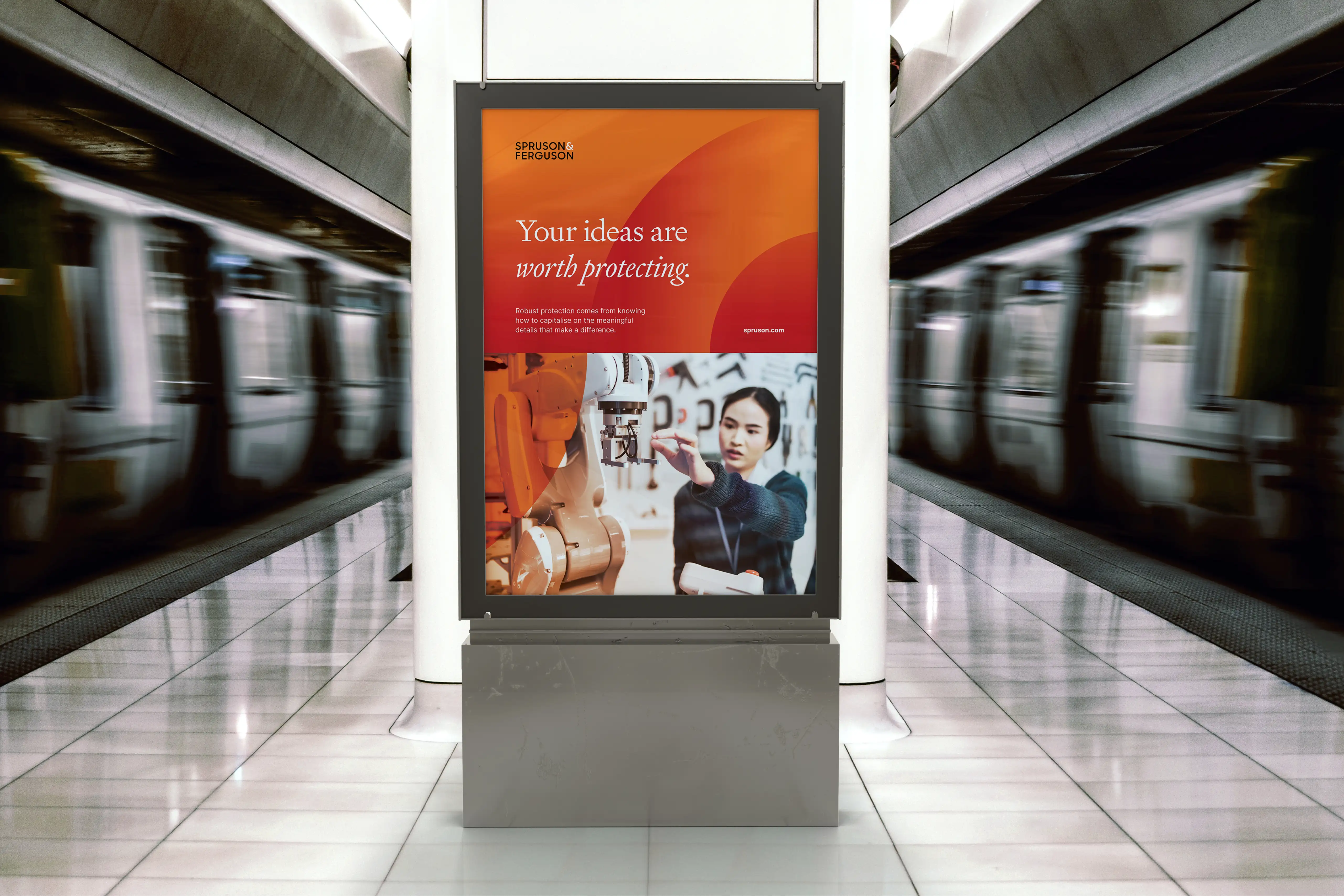 Backlit advertising panel in a train station showing Spruson & Ferguson’s campaign with a warm orange gradient, the message “Your ideas are worth protecting.” and an image of a woman working with industrial robotics.