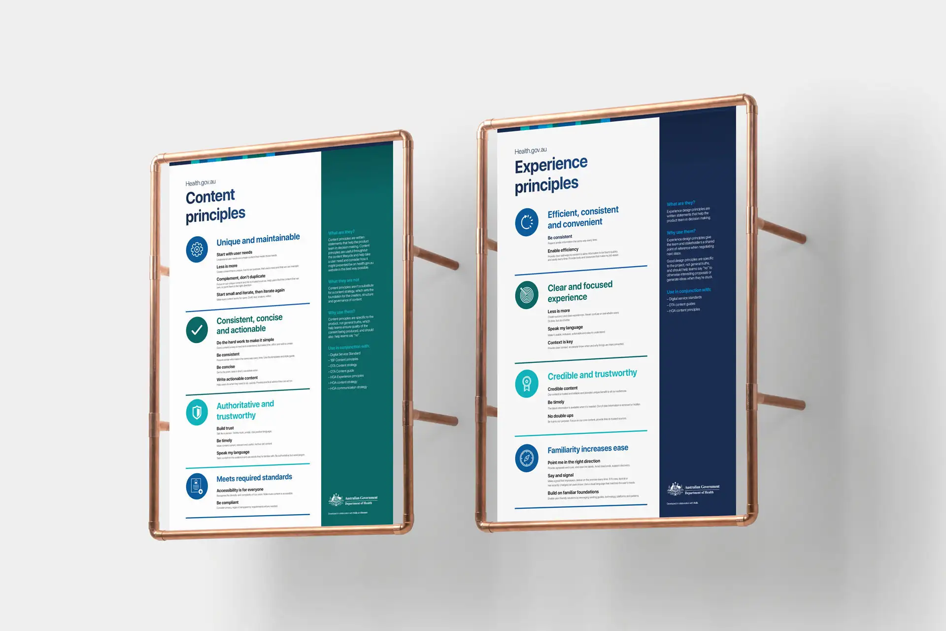 Two copper-framed posters mounted on a wall displaying Health.gov.au content and experience principles.