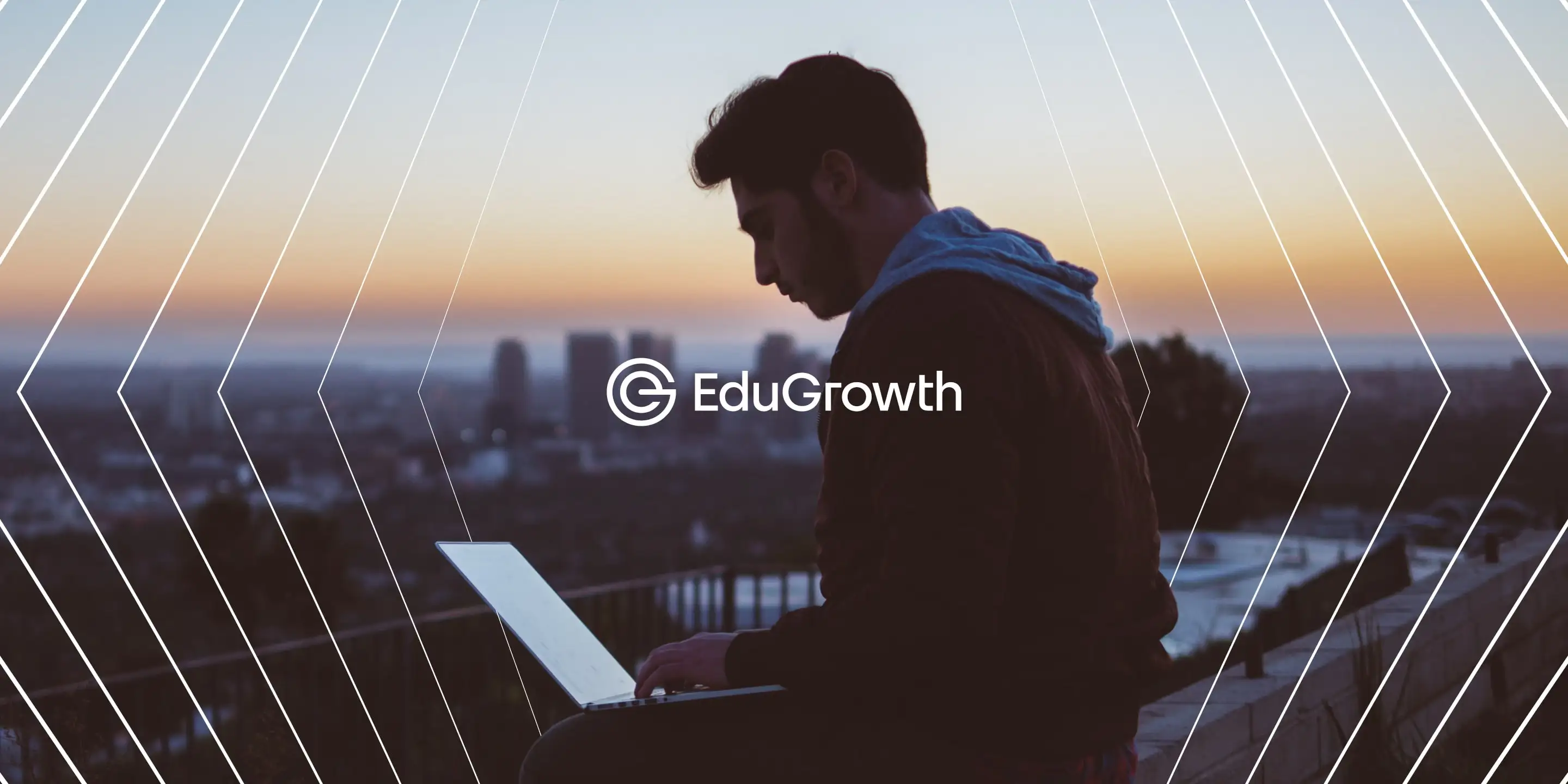 A young man working on a laptop outdoors at sunset with a city skyline in the background and EduGrowth logo overlayed.