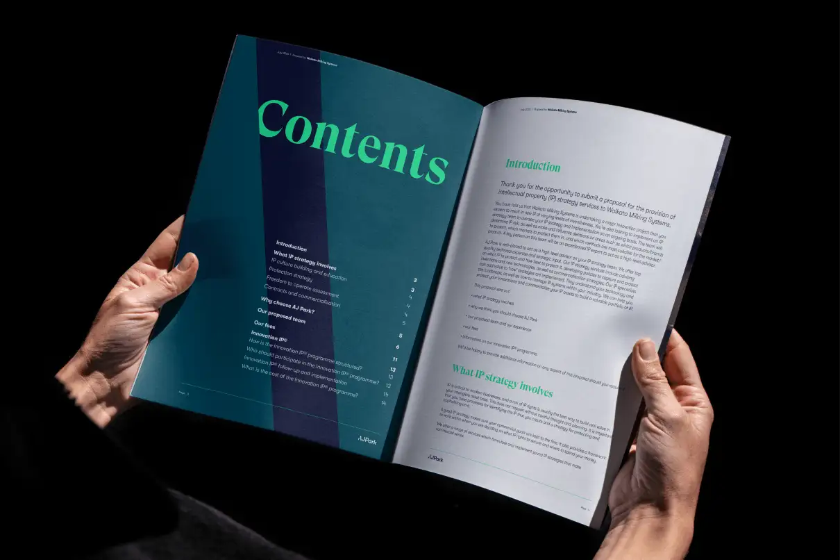 Hands holding an open AJ Park booklet showing the contents page on the left and introductory text on the right.