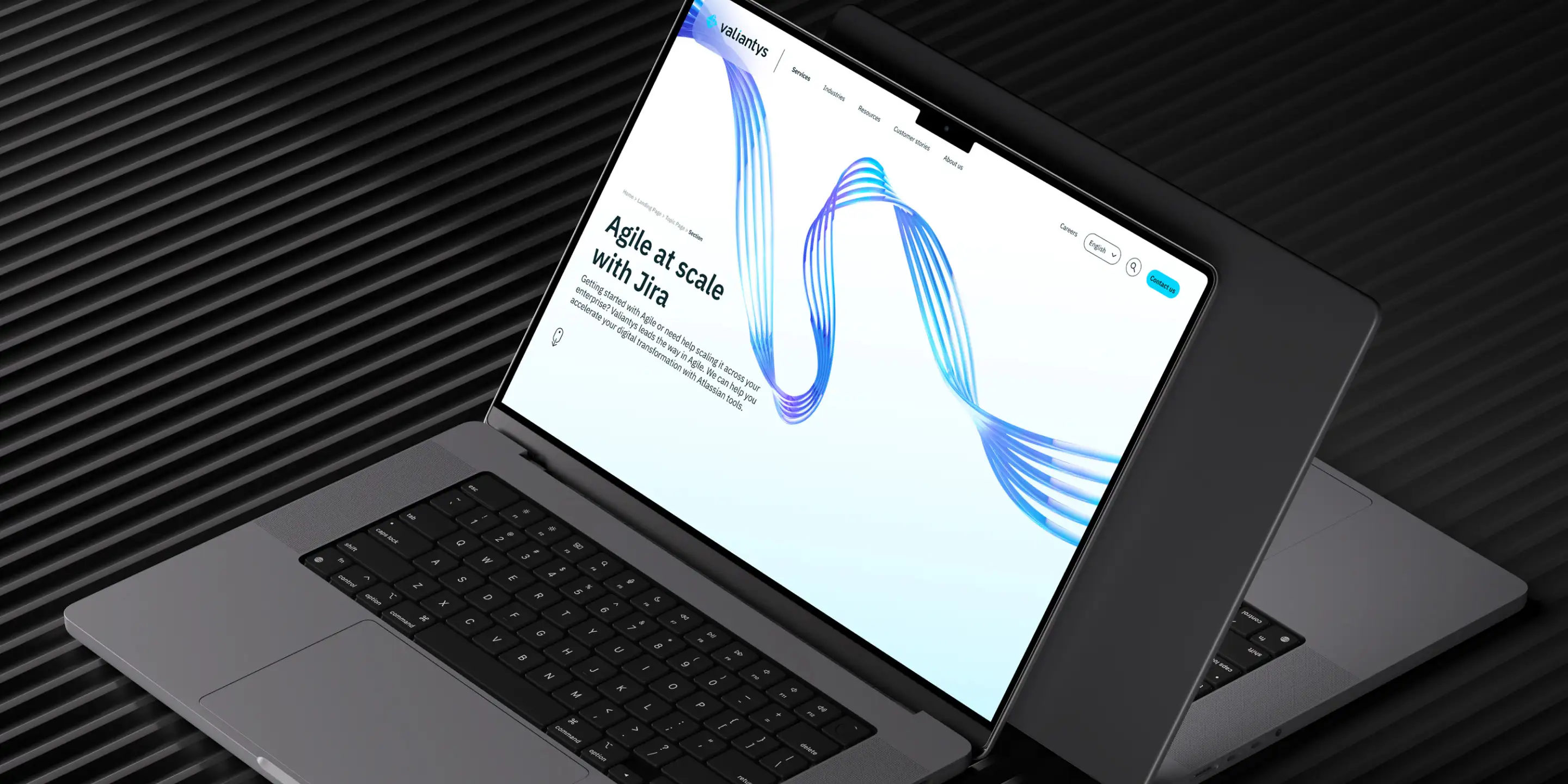 Open laptop displaying a Valiantys webpage titled 'Agile at scale with Jira' with a blue abstract wave design on screen.