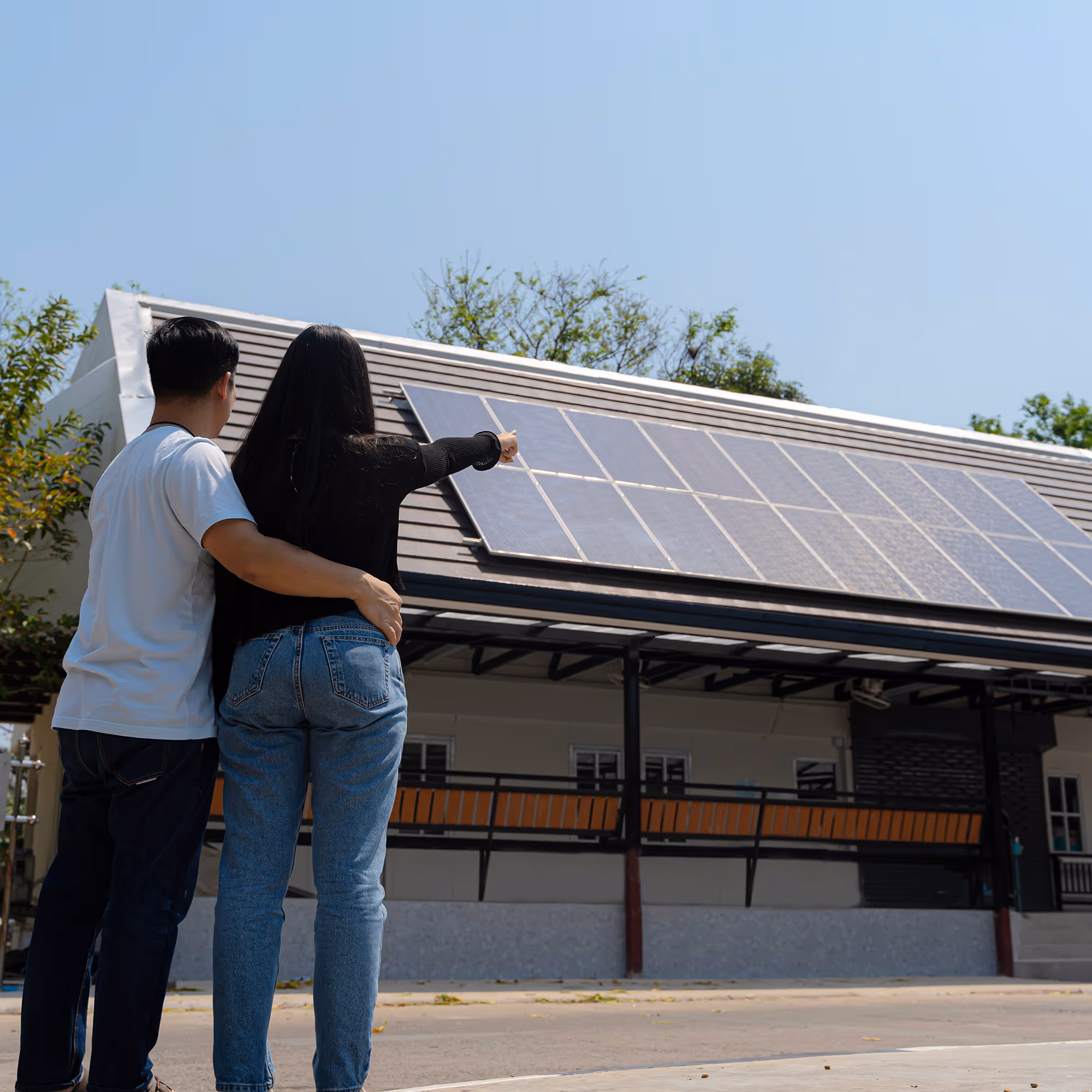 Couple pointing at house with solar panels.