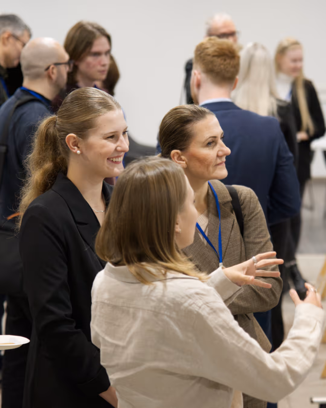 A group of professionals engaged in conversation during a networking event, with focus on three women talking.