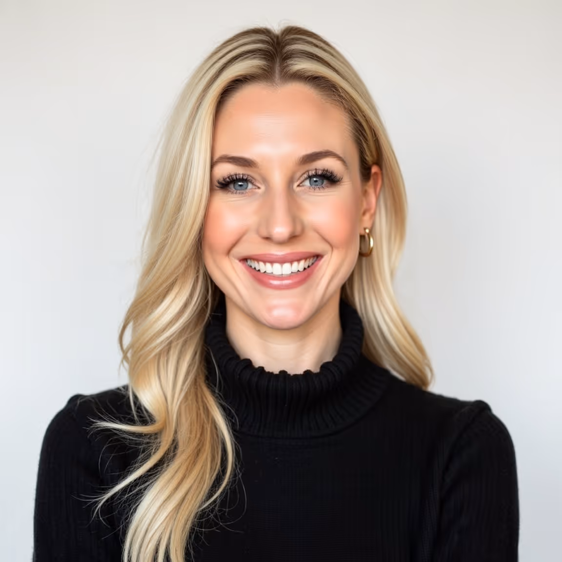 Smiling blonde woman with long hair wearing a black turtleneck sweater and gold hoop earrings.