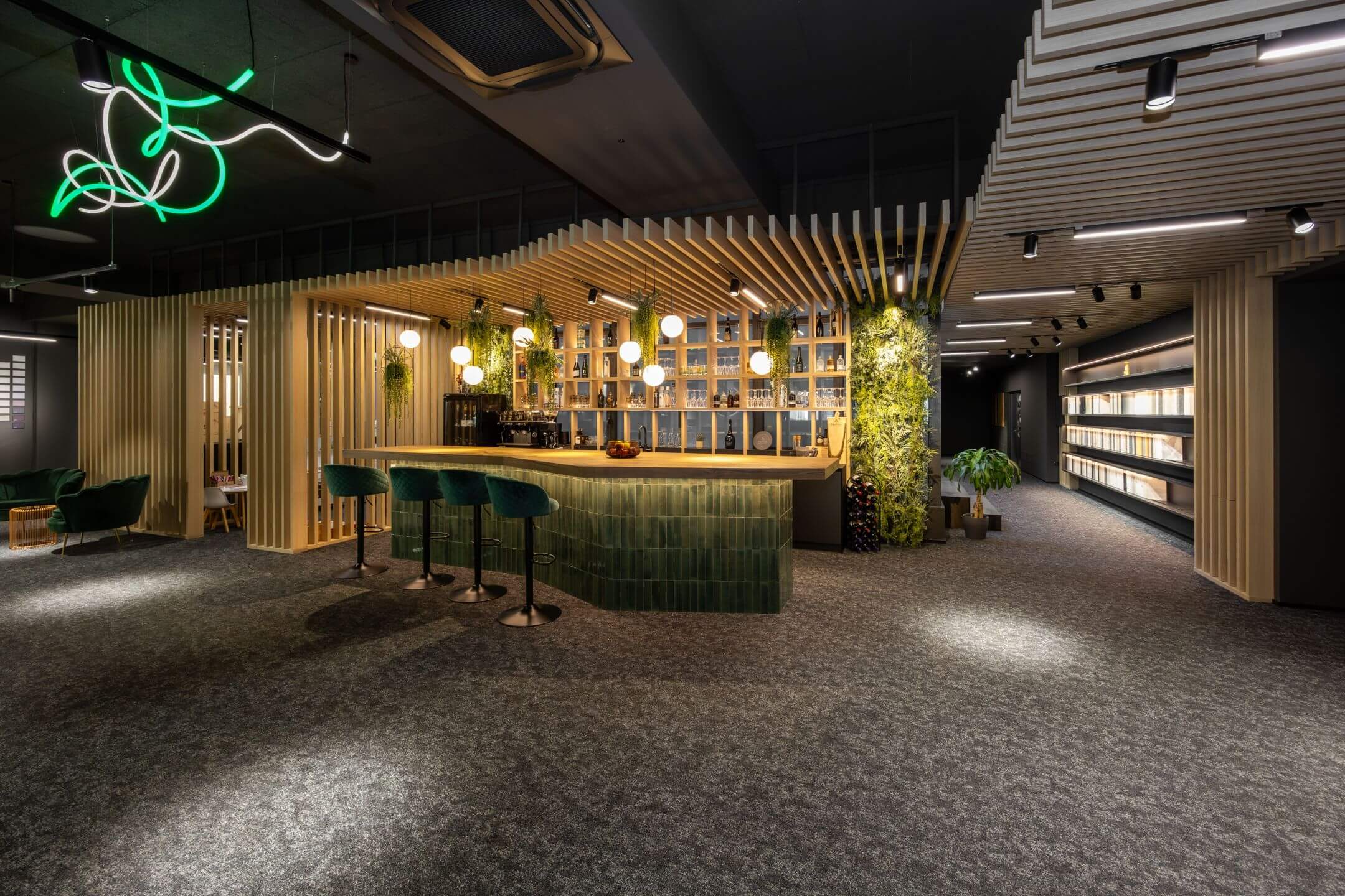 Moderner Showroom mit einer Bar aus grün gekacheltem Thekenbereich, grünen Barhockern, Holzlamellen an der Decke und hängenden Pflanzen.