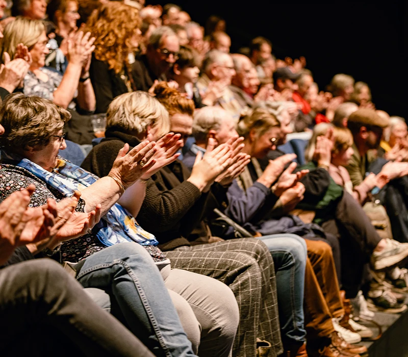 Publiek in een theater zit en klapt in de handen.