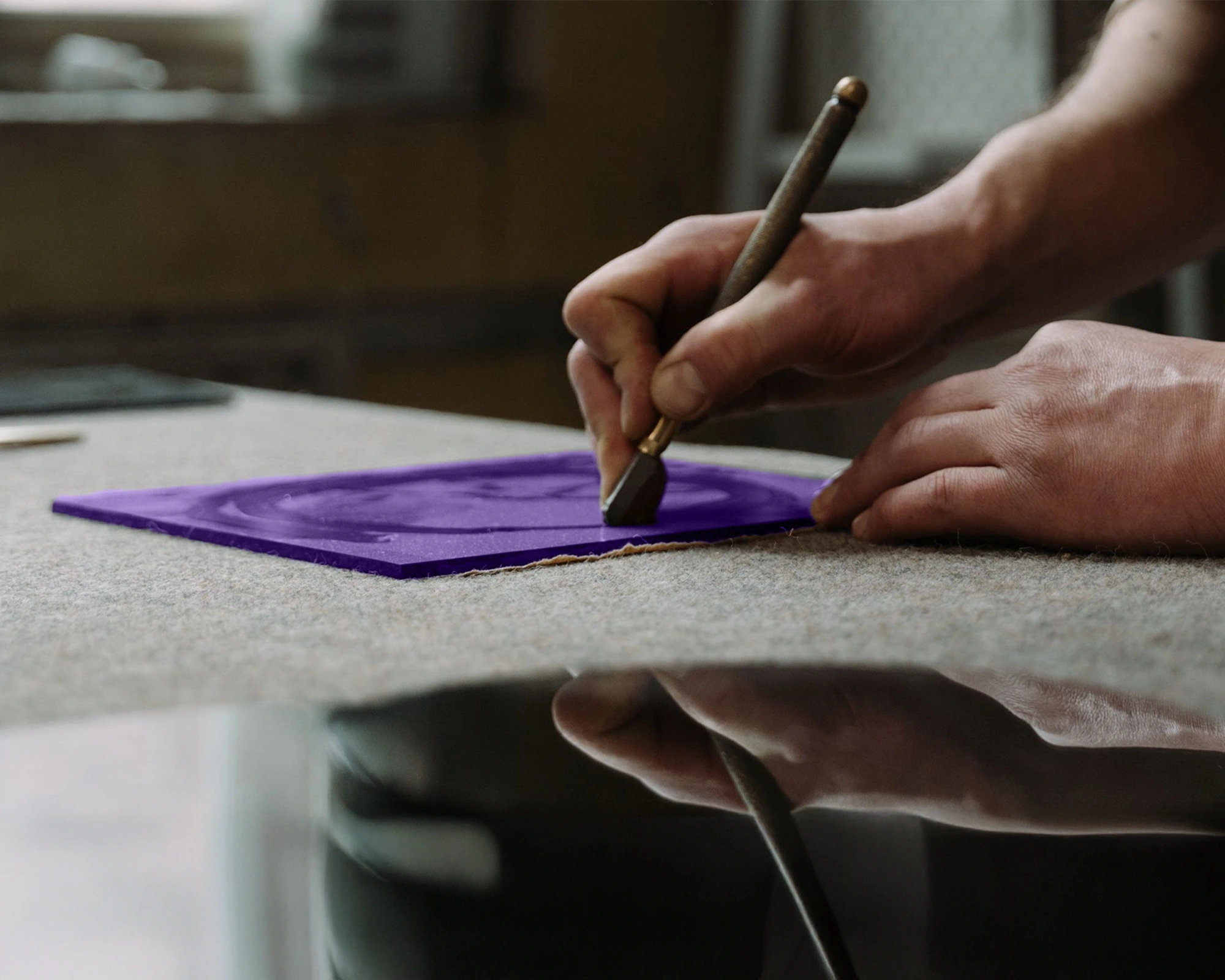 Close-up of a person engraving purple glass, representing LIMAH's technical delivery and governance expertise
