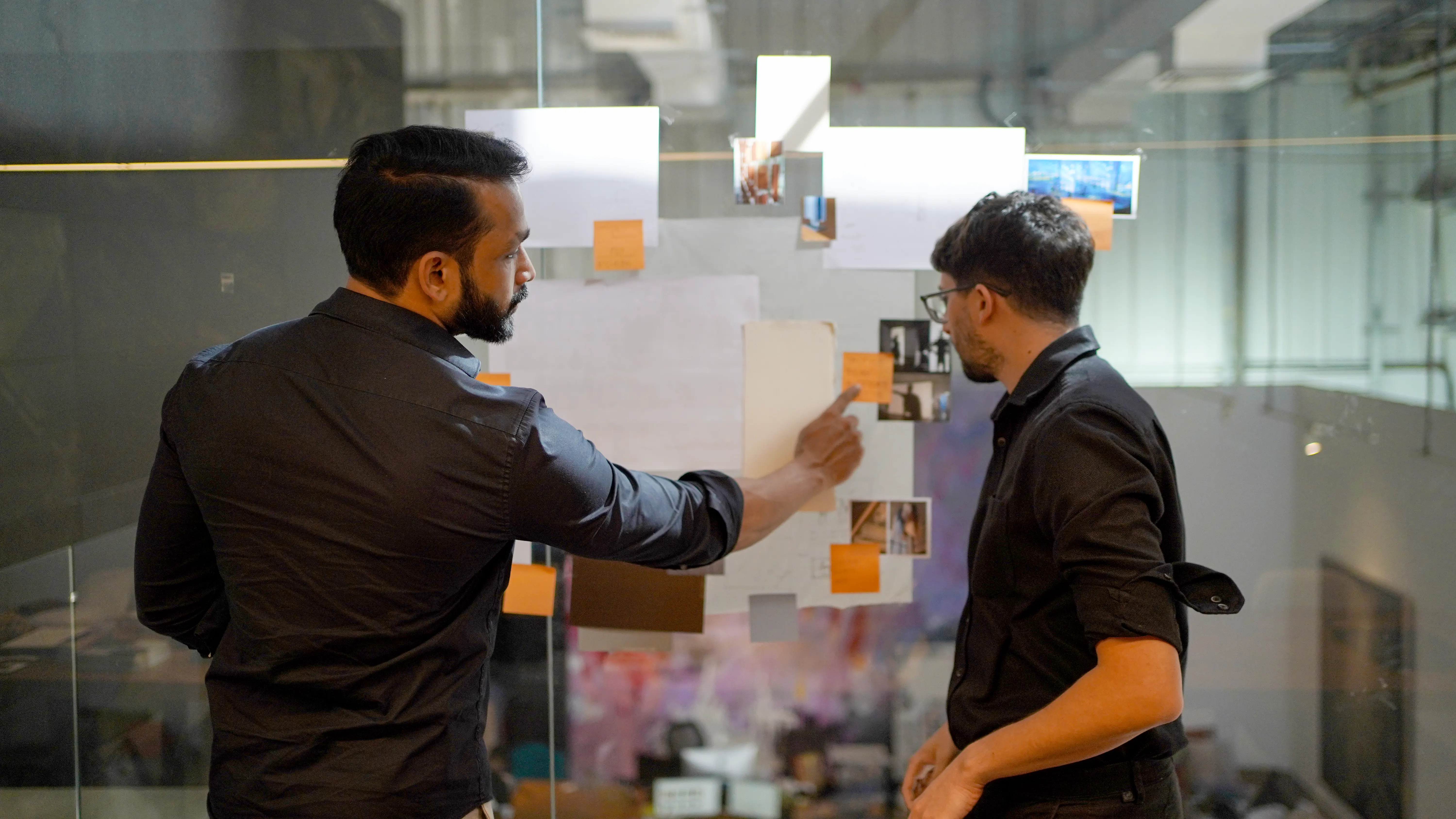 LIMAH designer and project coordinator reviewing strategy printouts pinned to a wall