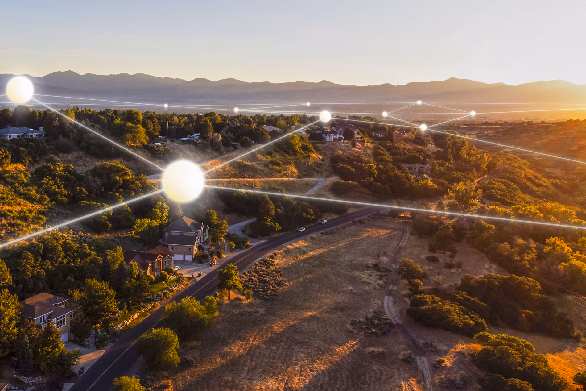 Landschaft mit Häusern, durchzogen von leuchtenden Verbindungslinien und Lichtpunkten, die ein digitales Netzwerk symbolisieren.