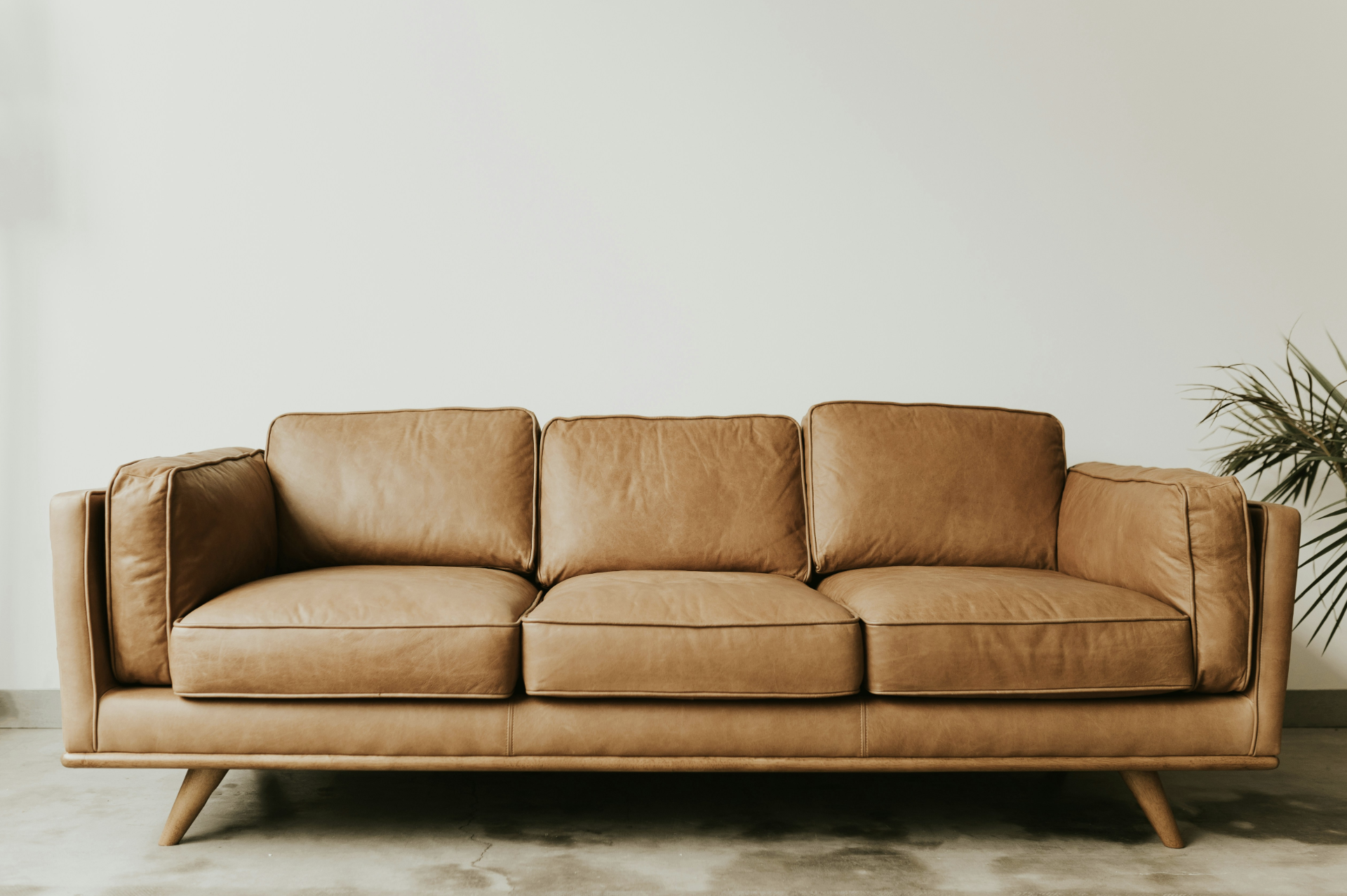 Modern brown leather sofa against a plain wall.