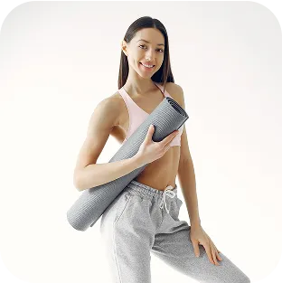 A woman holding a yoga mat in her right hand.