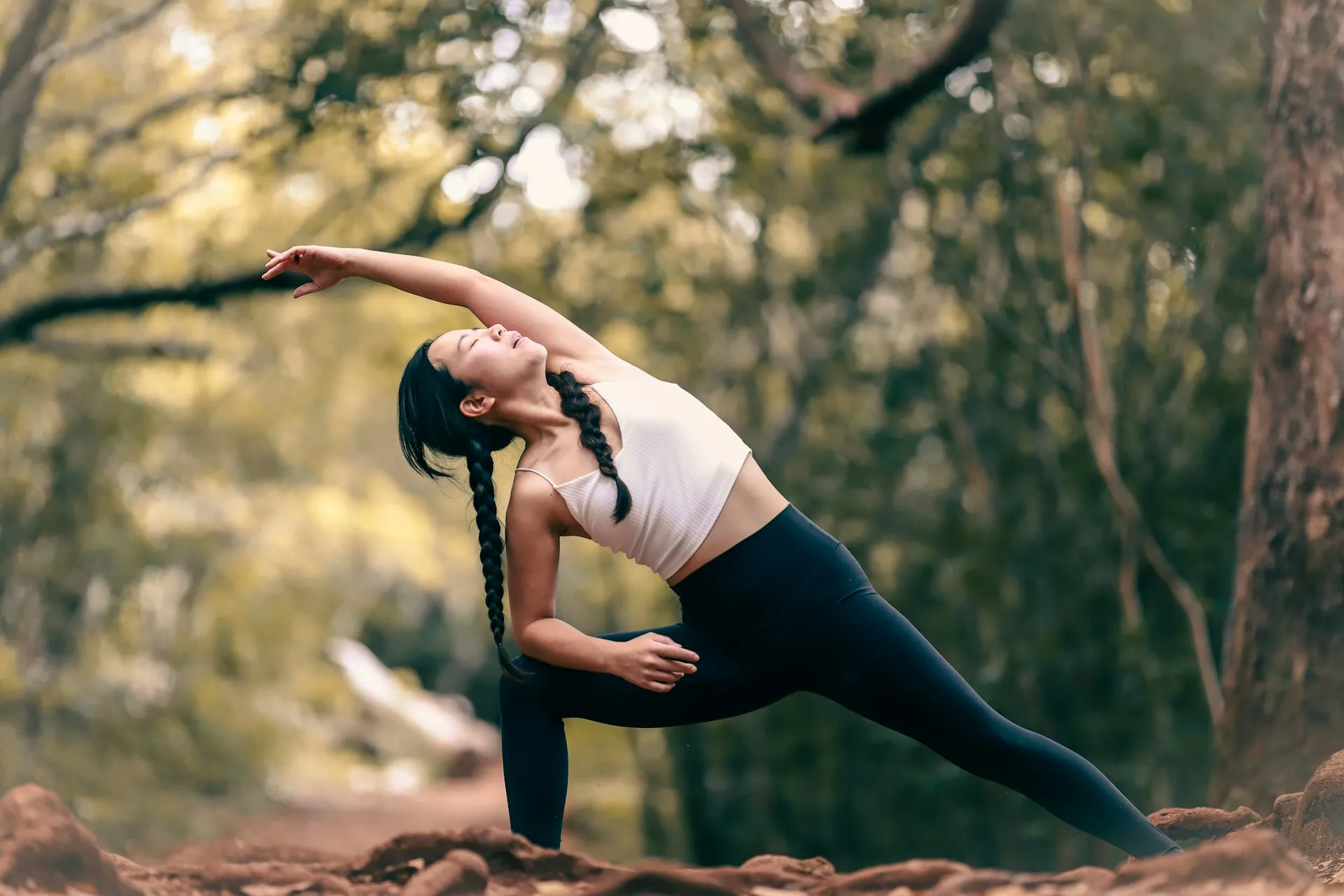 A woman doing a yoga pose in the woods.