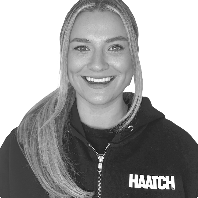 Smiling woman with long blonde hair wearing a black hoodie with the word 'HAATCH' on it.