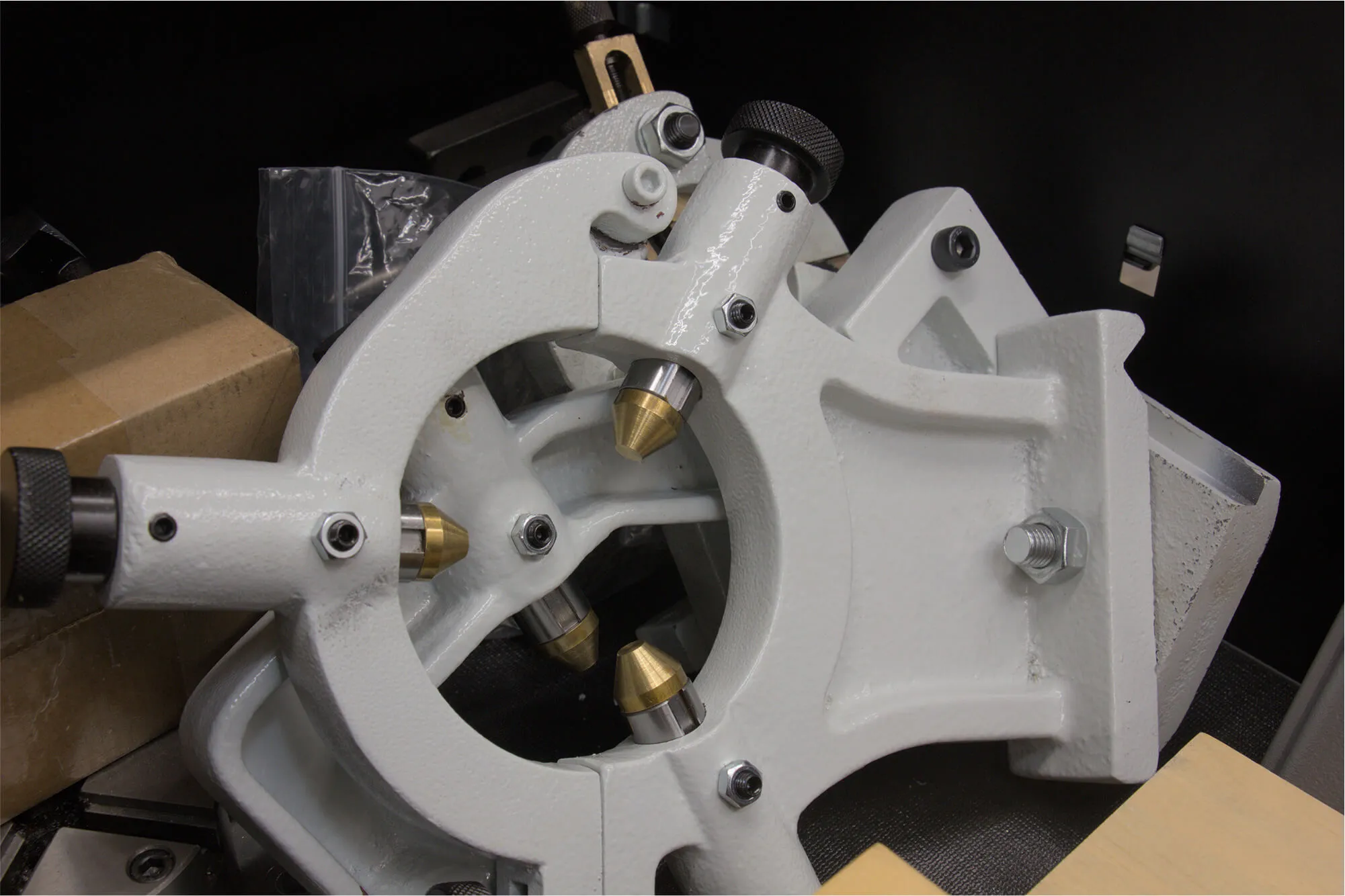 Specialized light gray machining fixture with precision brass components, illustrating the complexity of custom fabrication and prototyping tools available inside the Flatirons Rapid Prototyping workshop.