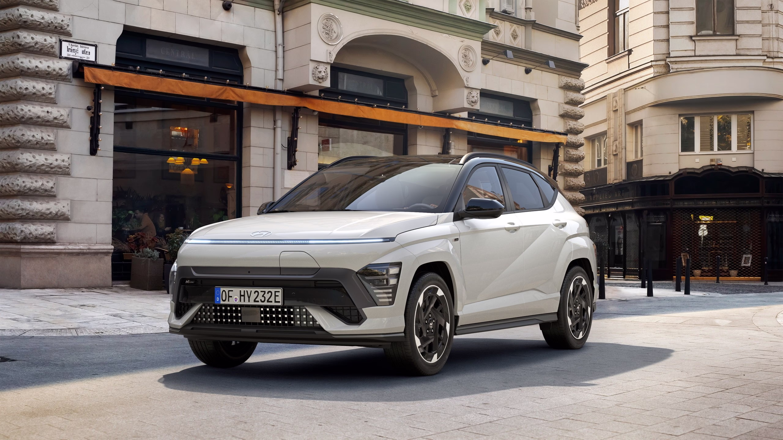 Hyundai electric SUV garée dans une rue pavée devant un bâtiment ancien avec des fenêtres et une enseigne orange.