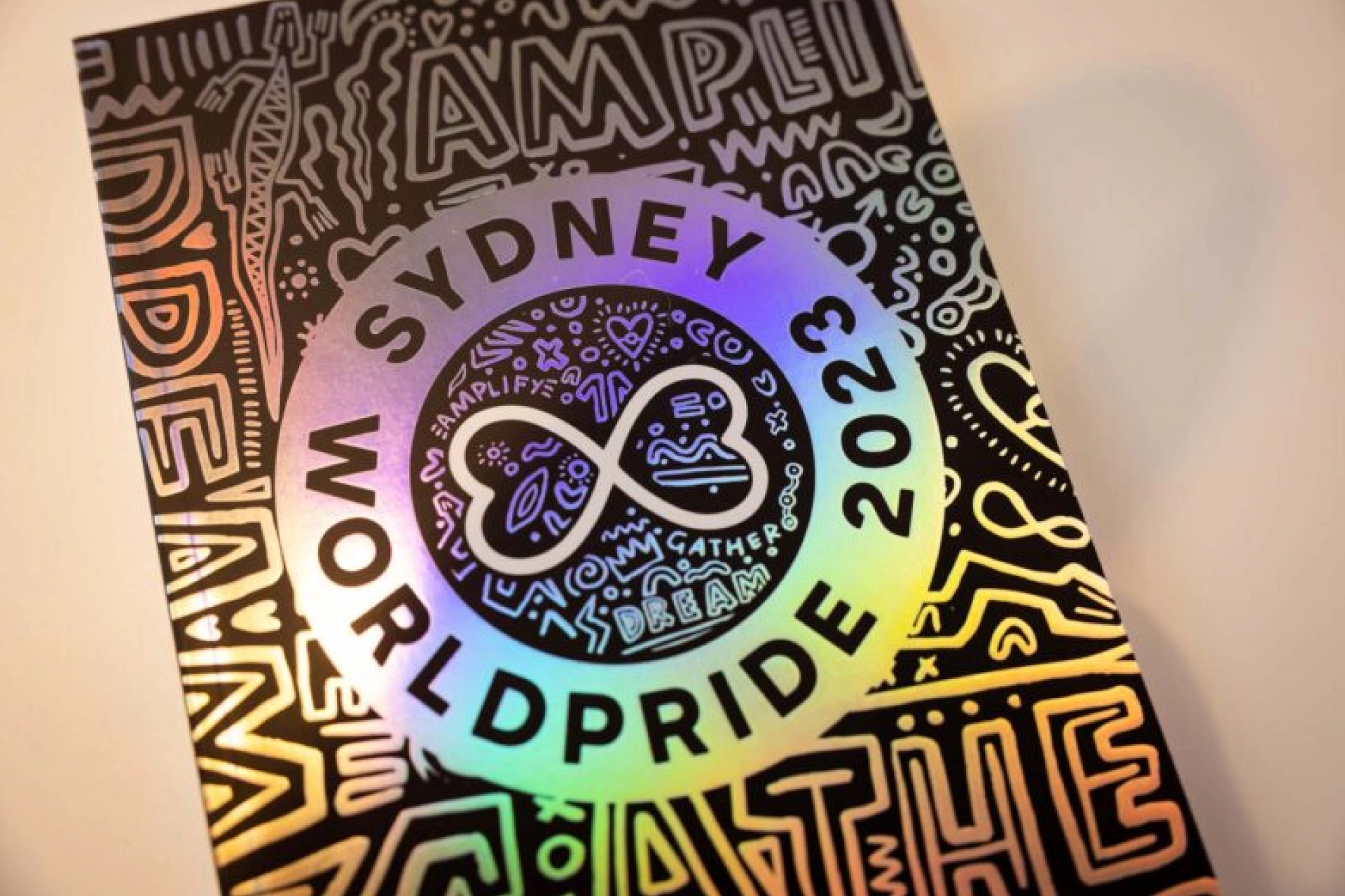 Circular sign displaying the Sydney WorldPride 2023 artwork with vibrant First Nations and LGBTQ+ design elements.
