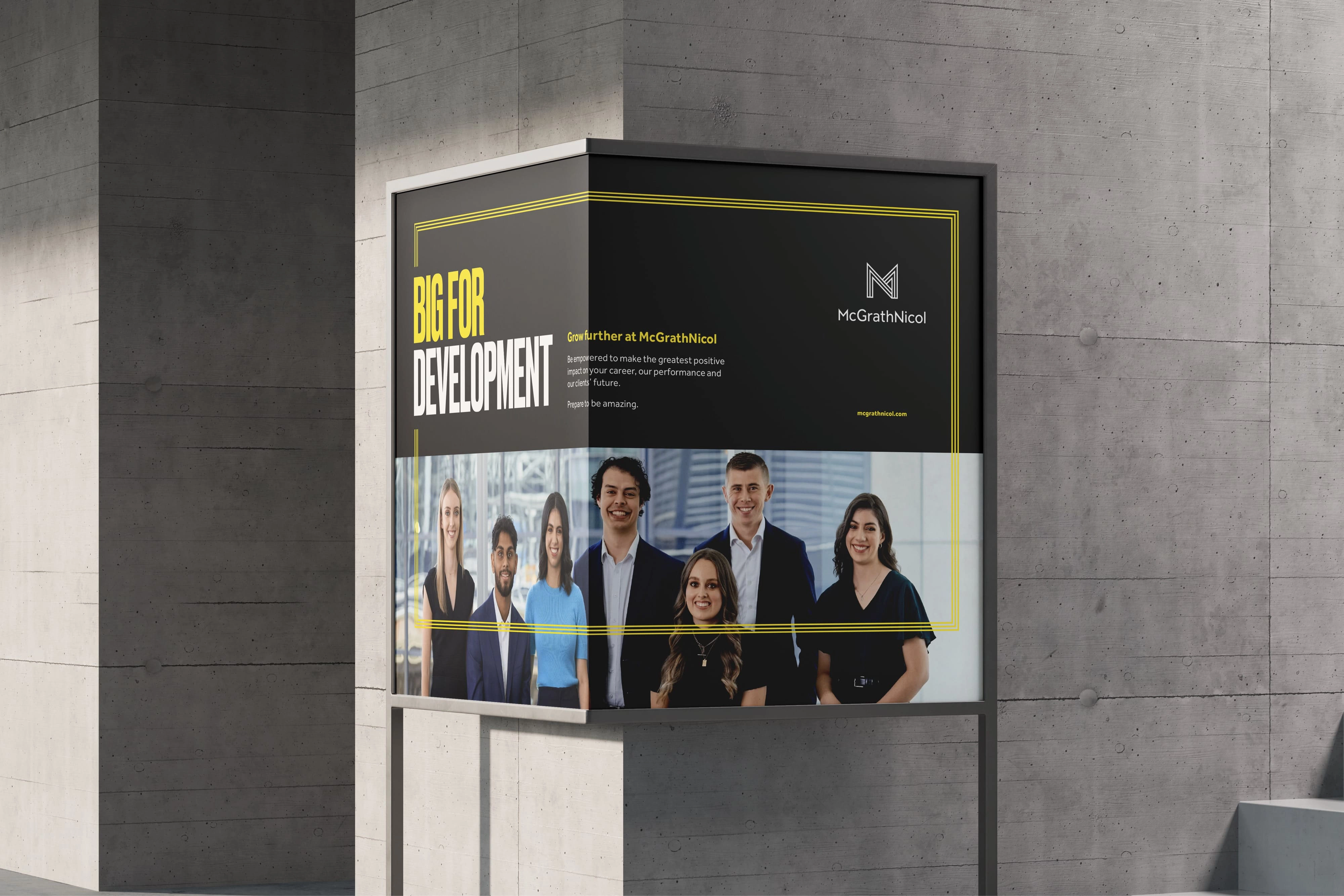 Large corner-mounted outdoor poster for McGrathNicol’s graduate campaign featuring the headline ‘Big For Development’ above a group portrait of graduates, displayed on a concrete building wall.