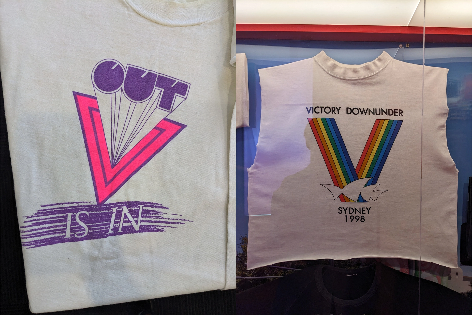 Two T-shirts from the ‘Designed with Pride’ exhibition featuring queer graphic design artwork: one reading ‘Out is In,’ the other with a rainbow ‘Victory’ graphic.