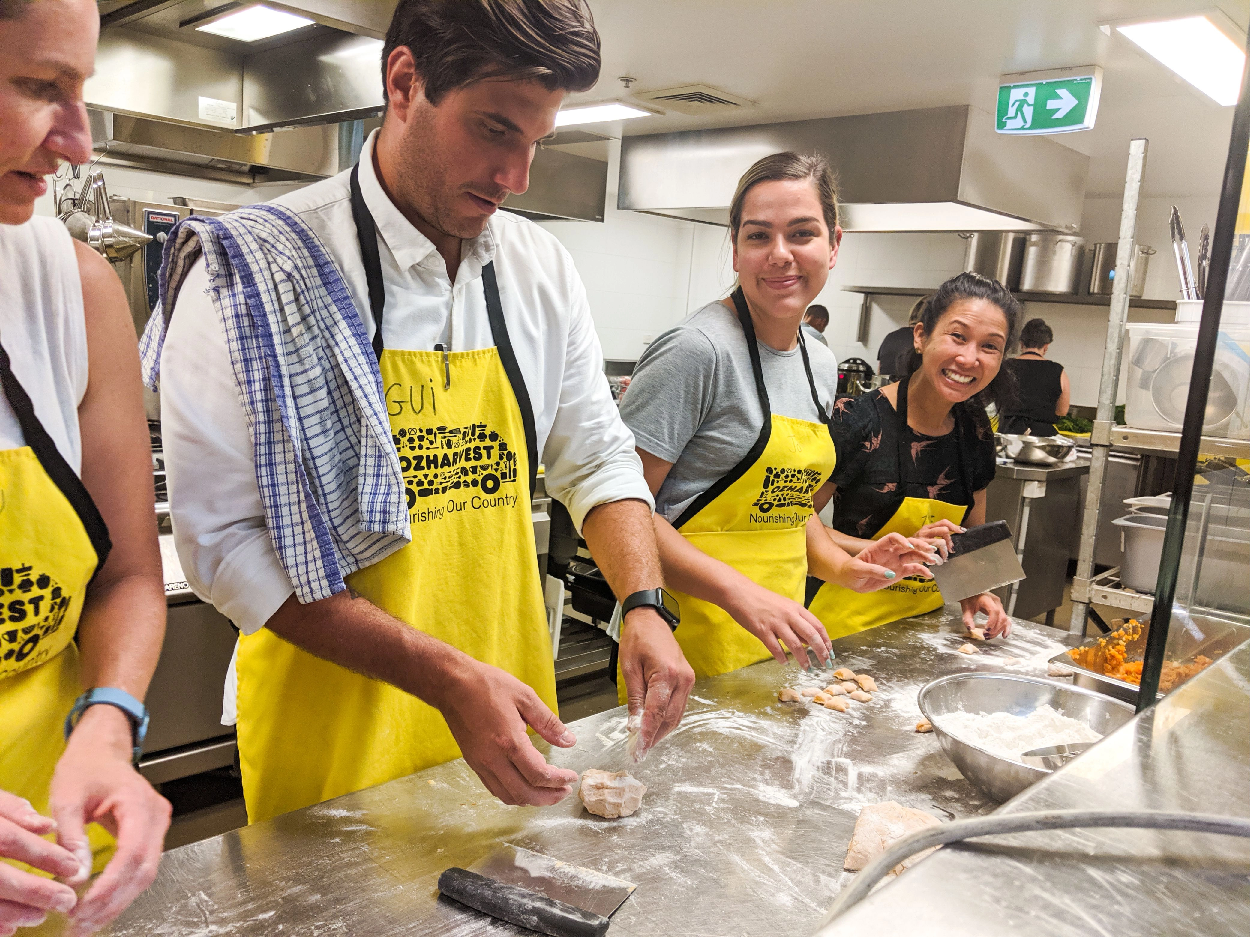 Folk team members making gnocchi together at a stainless-steel kitchen bench.