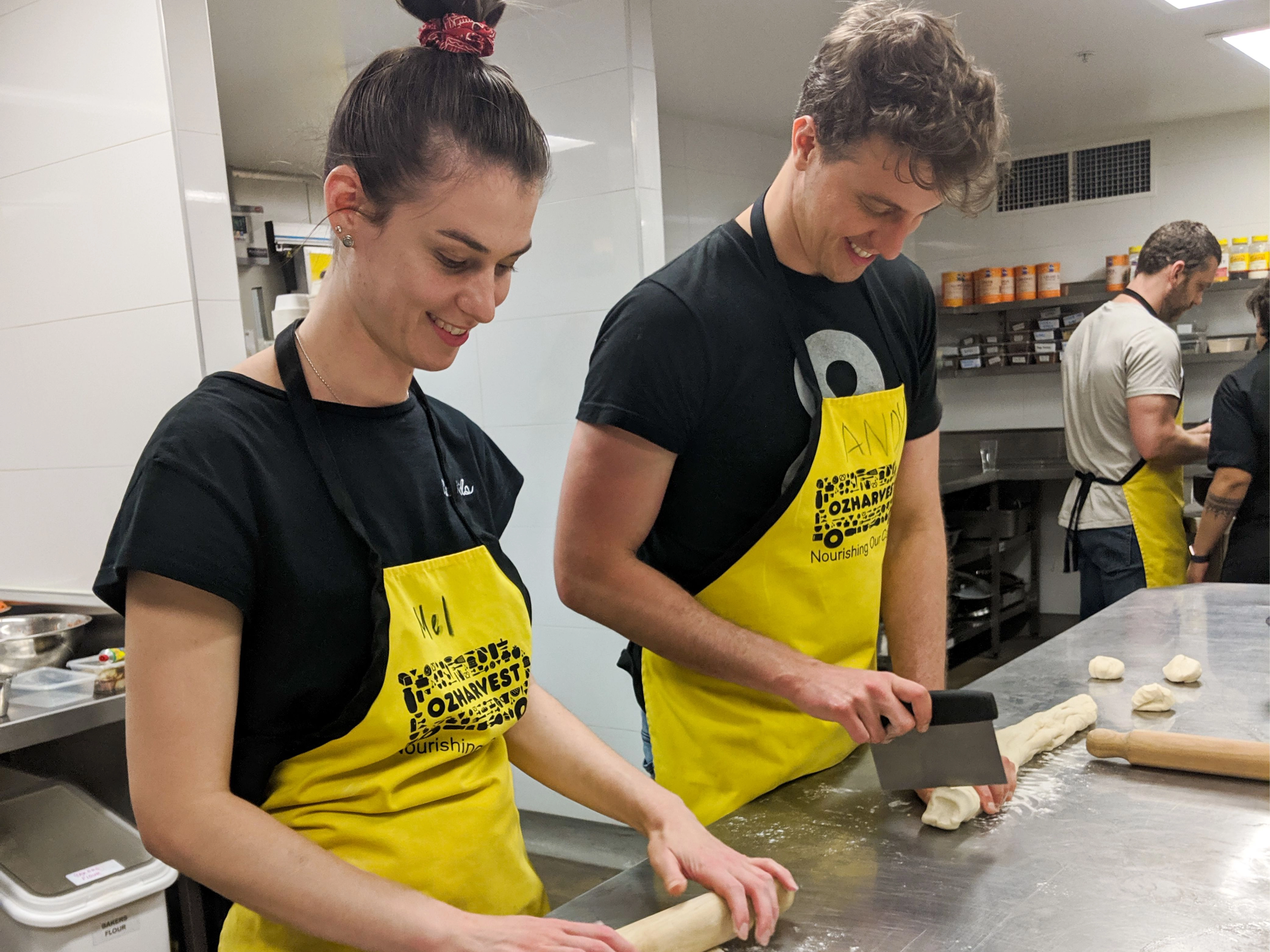 Two team members rolling and cutting dough.