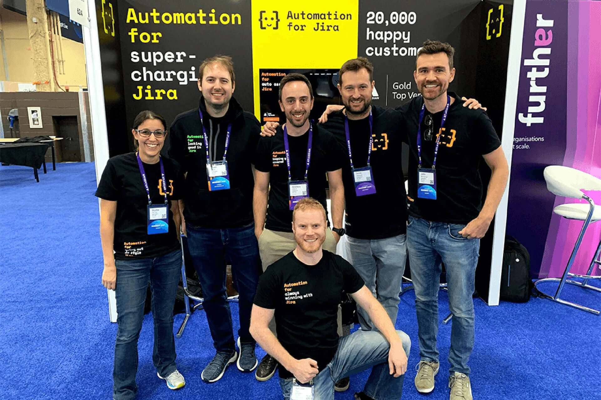 The Code Barrel team posing at a conference booth for Automation for Jira, wearing branded shirts and badges.