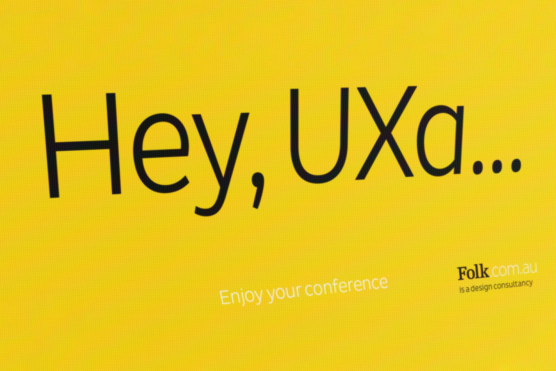 Yellow poster reading ‘Hey, UXa… Enjoy your conference’ used for Folk’s presence at UX Australia 2019.