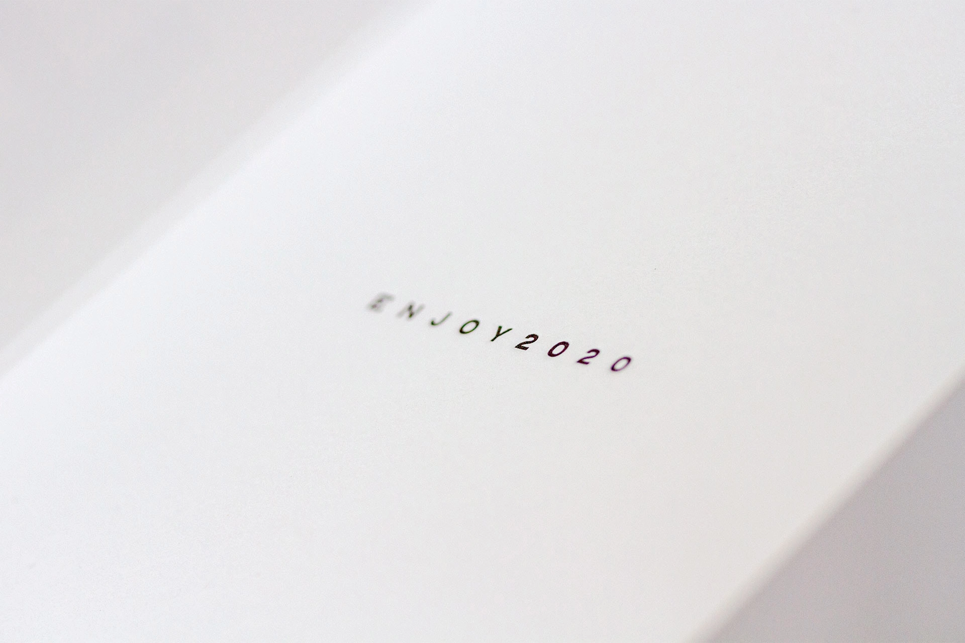 Minimal white folded card with the small printed title ‘ENJOY2020’ on the front.
