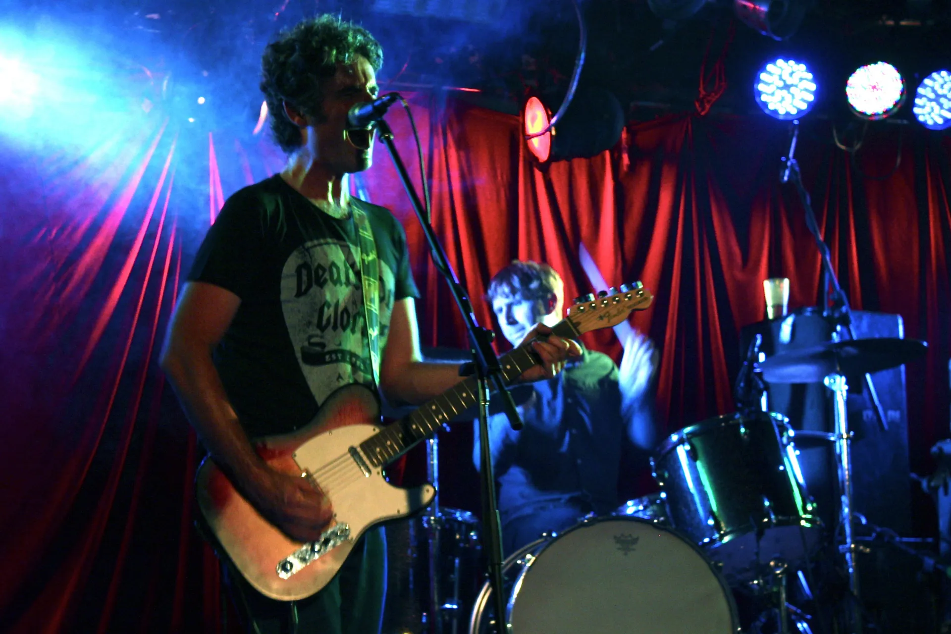 Musicians performing on stage at the Annandale Hotel under bright coloured stage lights.