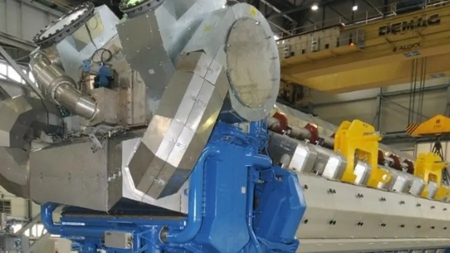 Large industrial engine with metallic and blue components inside a factory setting.