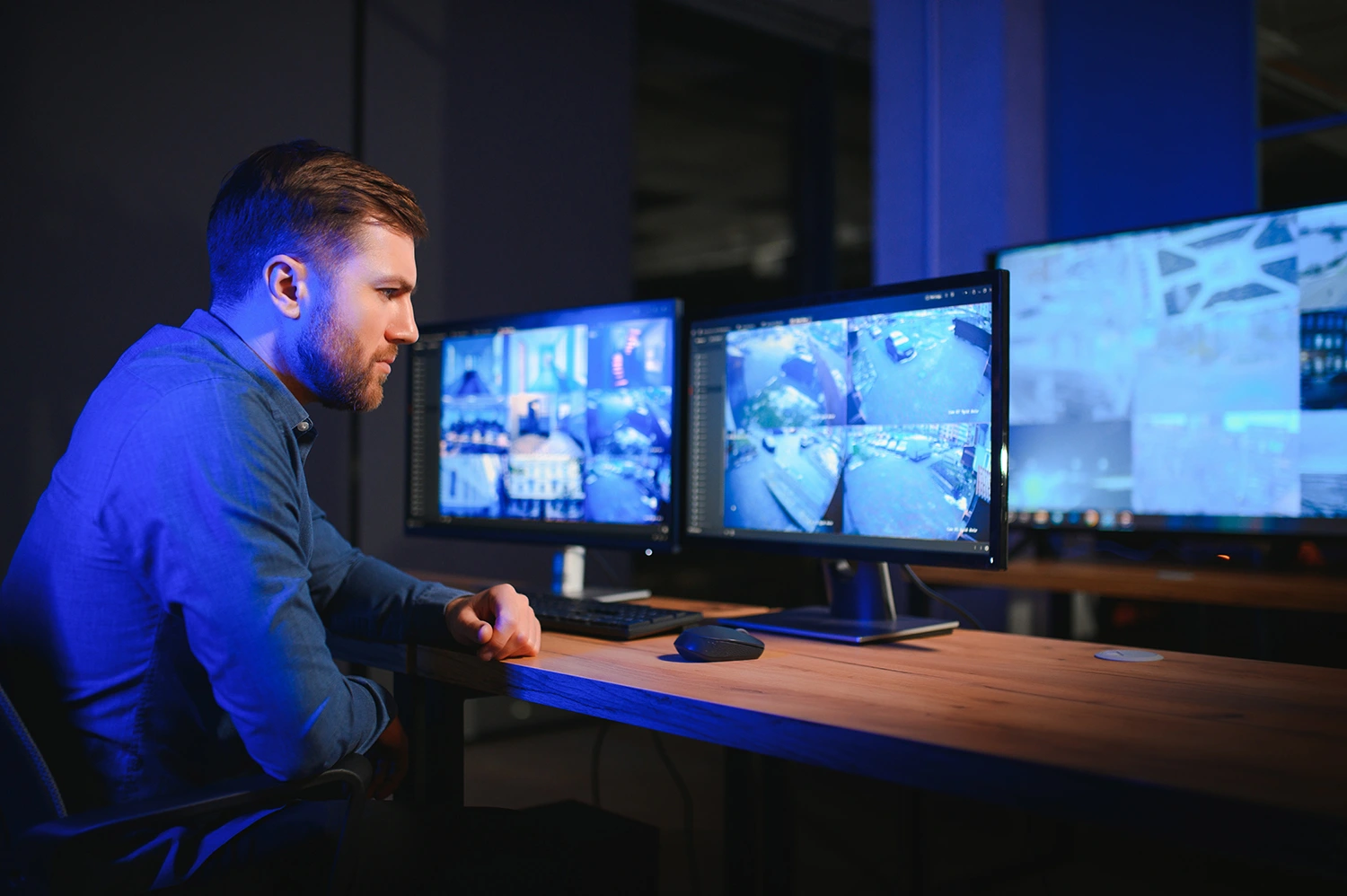 Een beveiliger die naar camerabeelden kijkt in een meldkamer