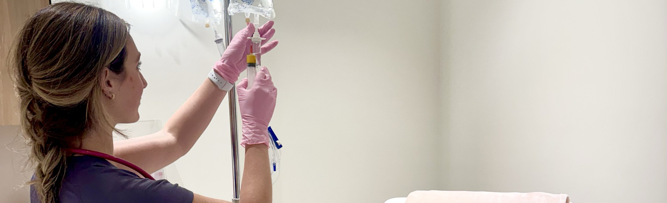 Materna nurse hanging an IV hydration bag beside a treatment chair
