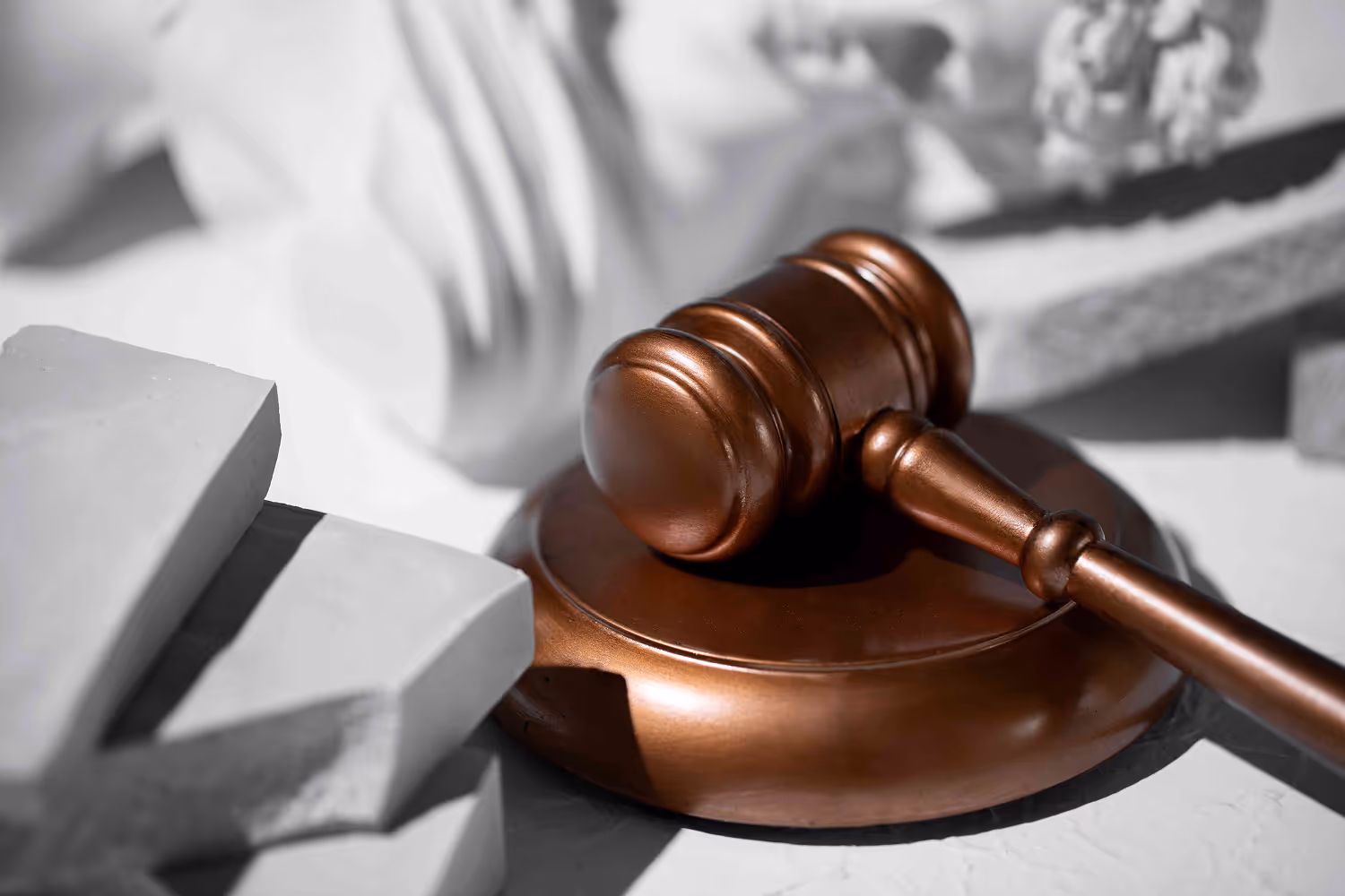 Bronze judge’s gavel resting on stone with classical columns in the background, symbolizing the court and rule of law.