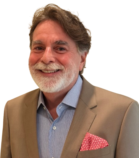Smiling older man with gray hair and beard wearing a tan blazer, blue shirt, and red patterned pocket square.