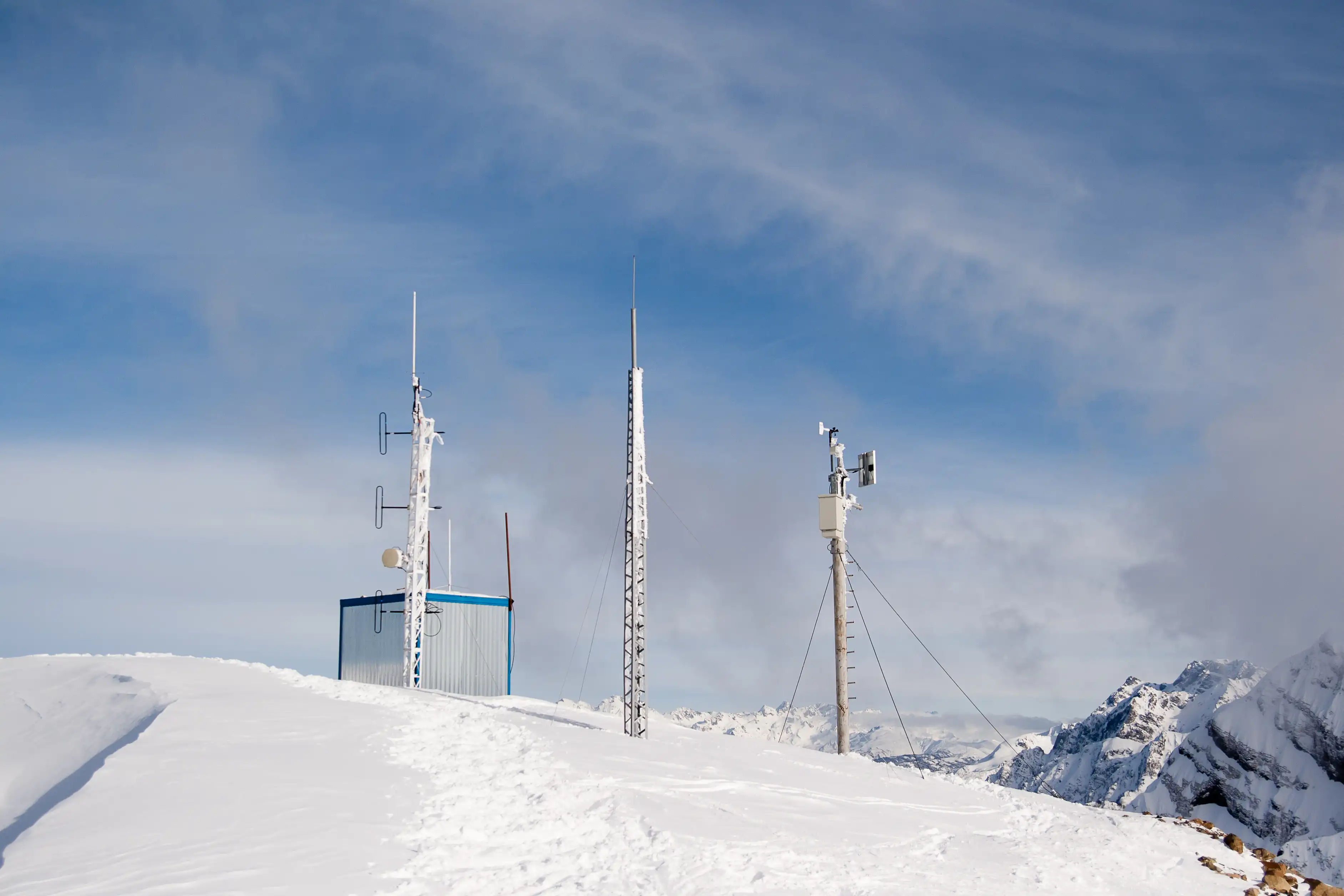 Remote communications and monitoring equipment installed in a snow-covered mountain environment.