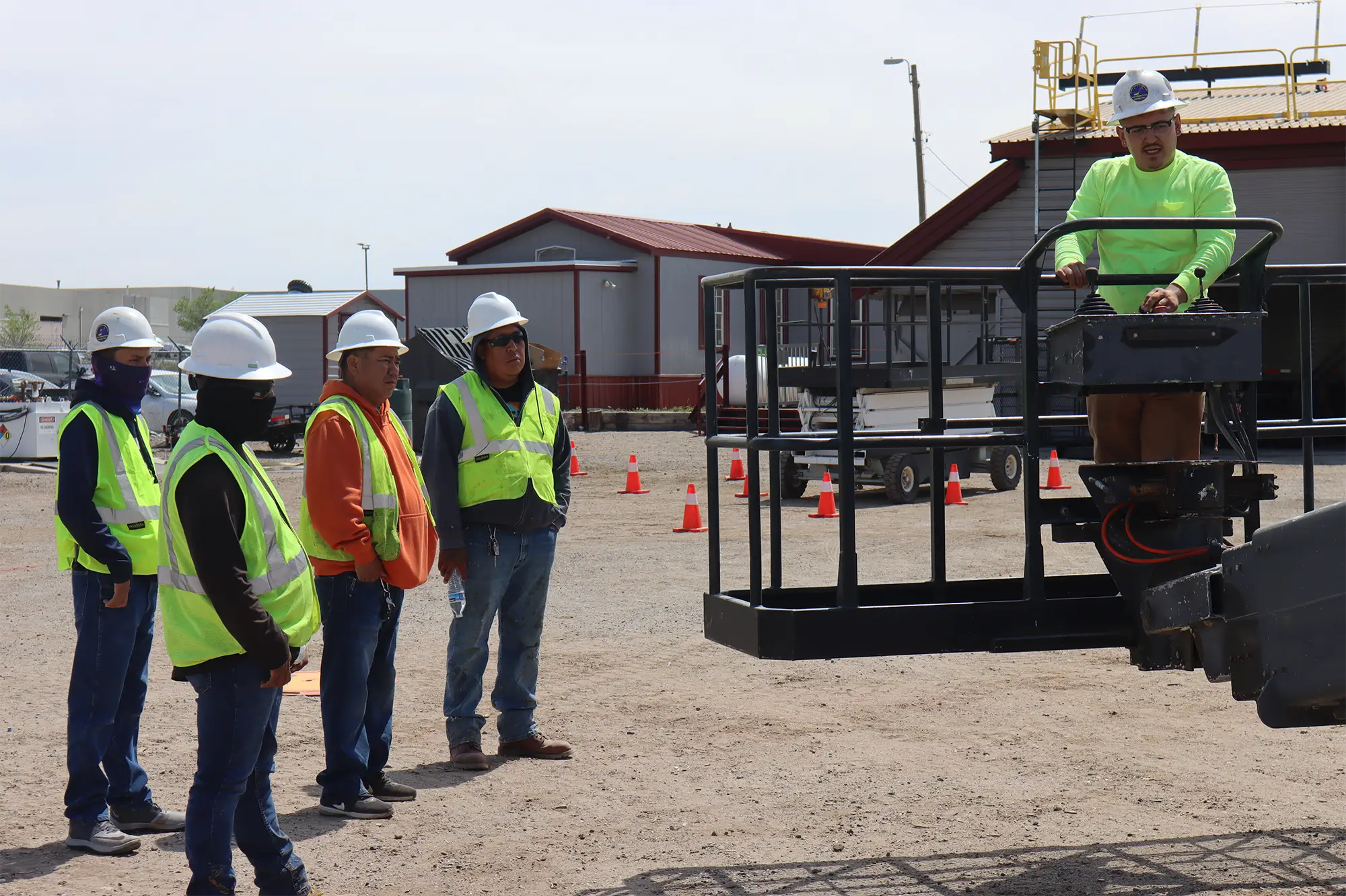 Instructor demonstrating aerial work platform operation to construction workers in safety gear during OSHA training session.