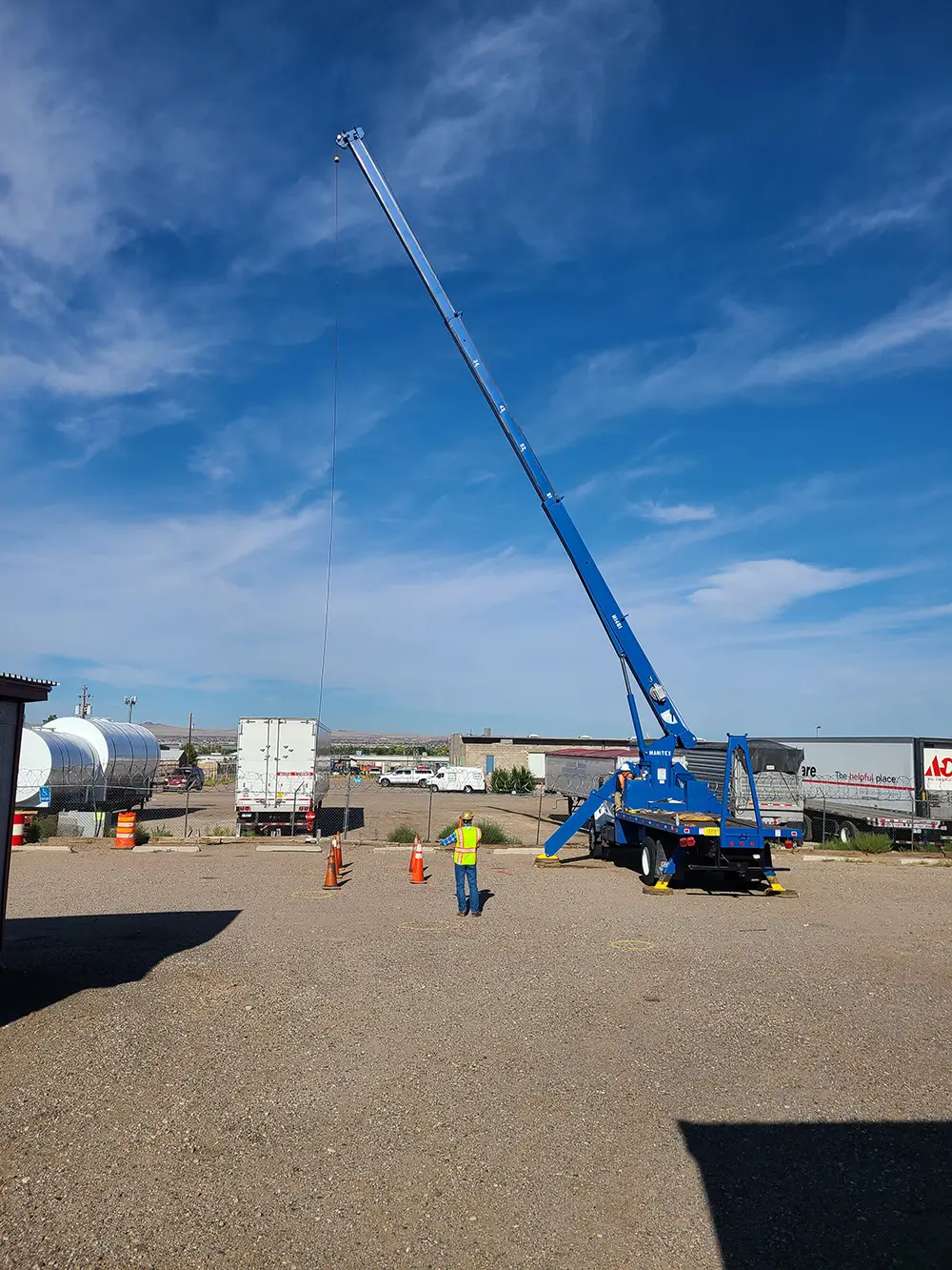 Instructor guiding a student operating a blue mobile crane during outdoor crane operator training in Albuquerque.