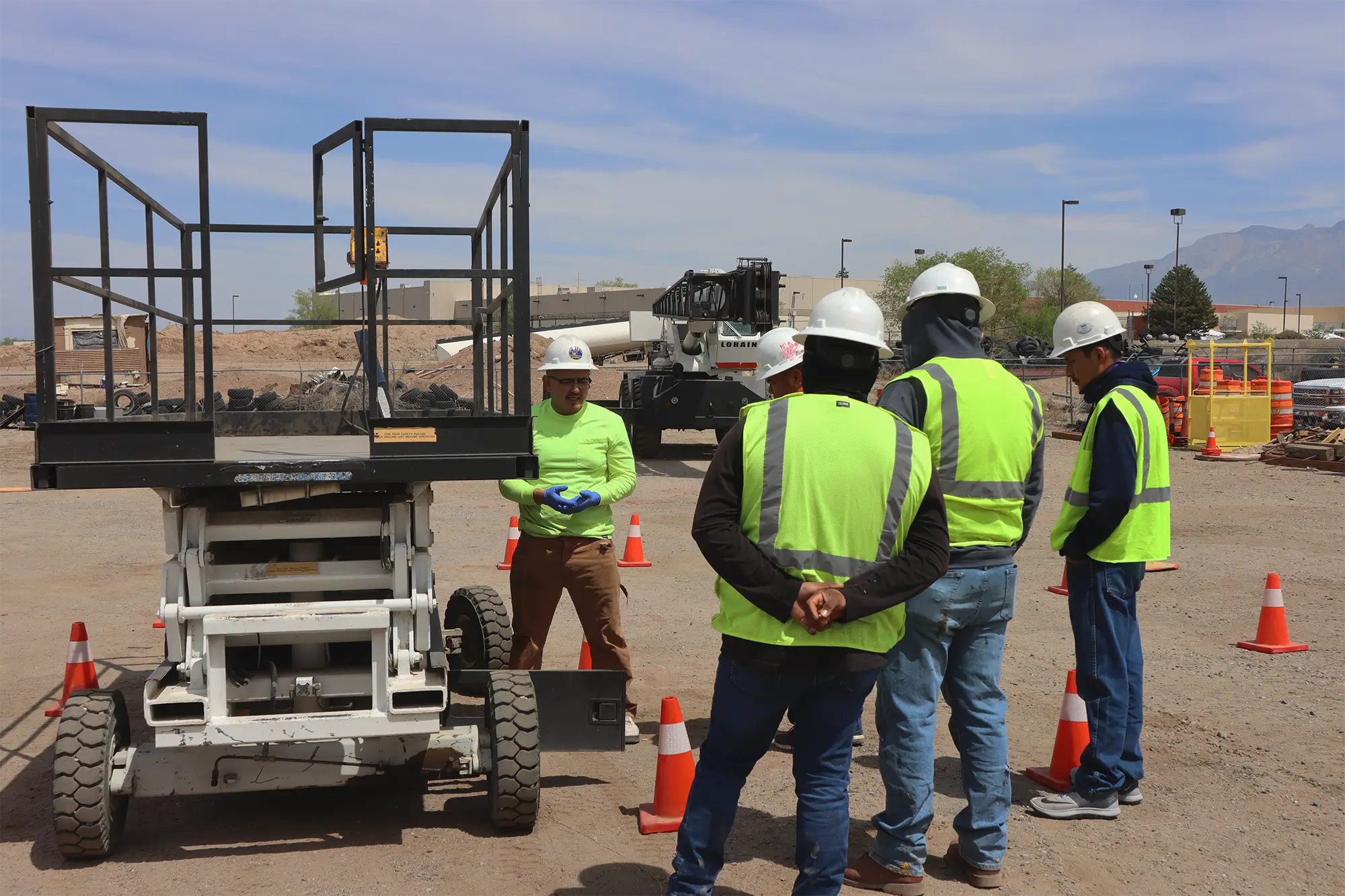Instructor demonstrating aerial lift safety procedures while students in hard hats and vests observe during training in Albuquerque.