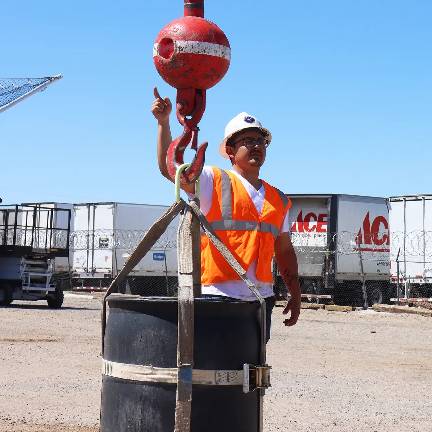 Student in high-visibility vest demonstrating advanced rigging and hand signaling while guiding a suspended load during crane training in Albuquerque.