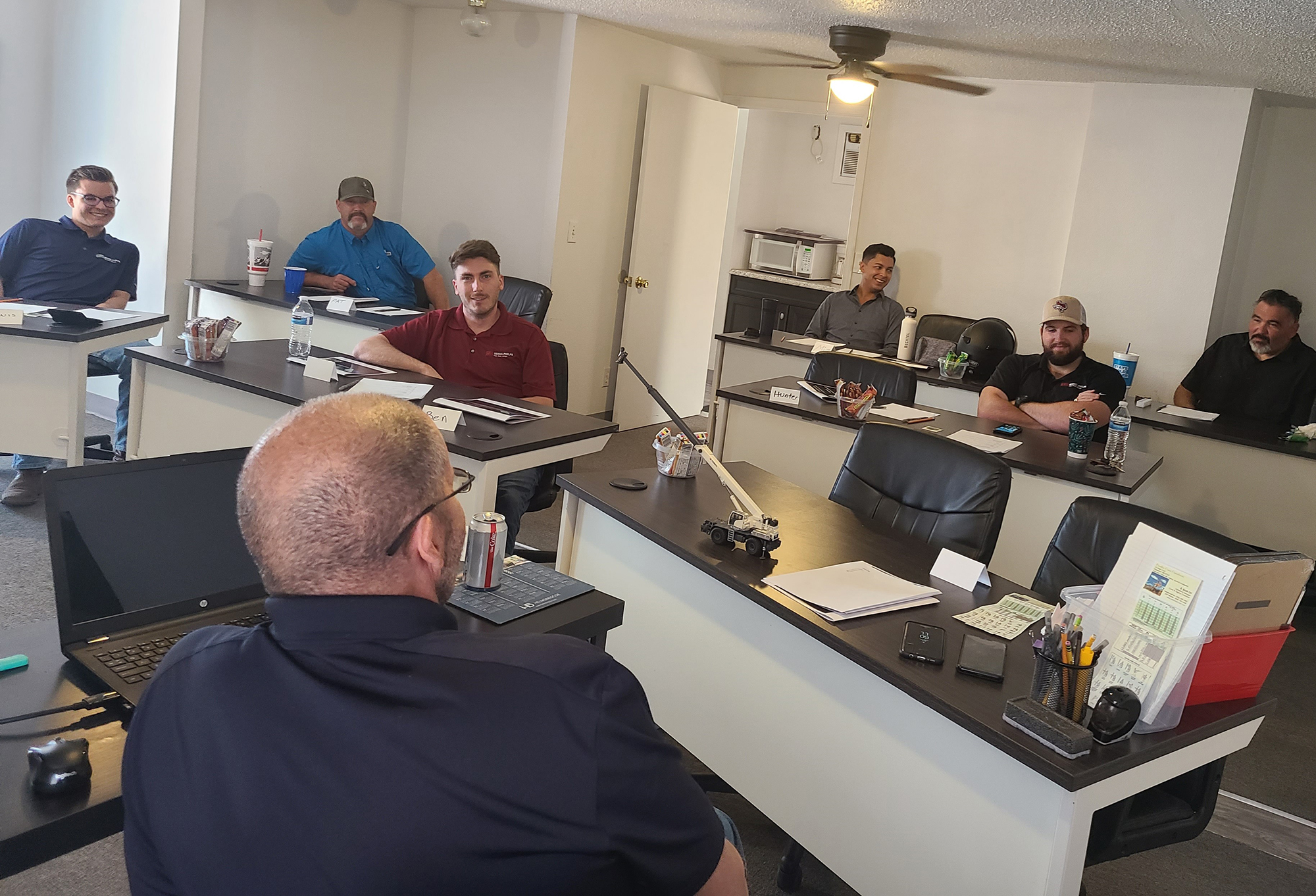 Student in high-visibility vest demonstrating advanced rigging and hand signaling while guiding a suspended load during crane training in Albuquerque.