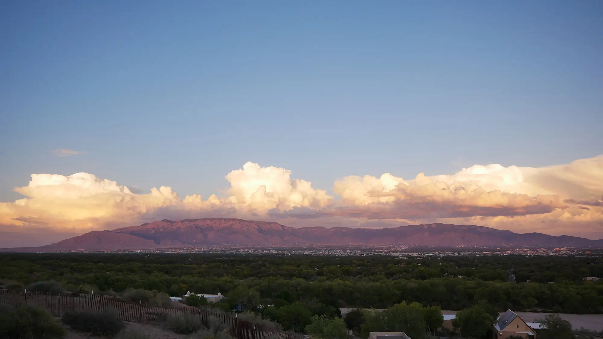Sunset view of the Sandia Mountains with glowing clouds over Albuquerque, New Mexico.