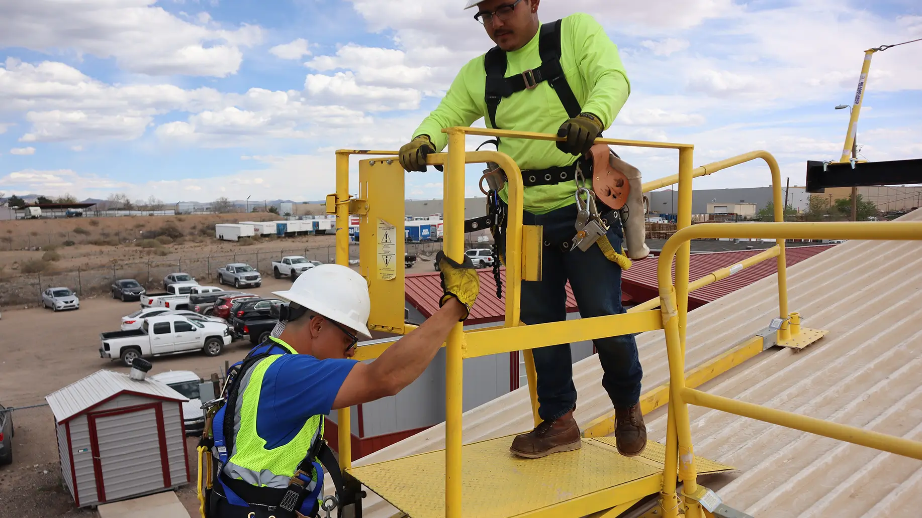 Worker in safety harness climbing with supervision during accredited fall protection training session.