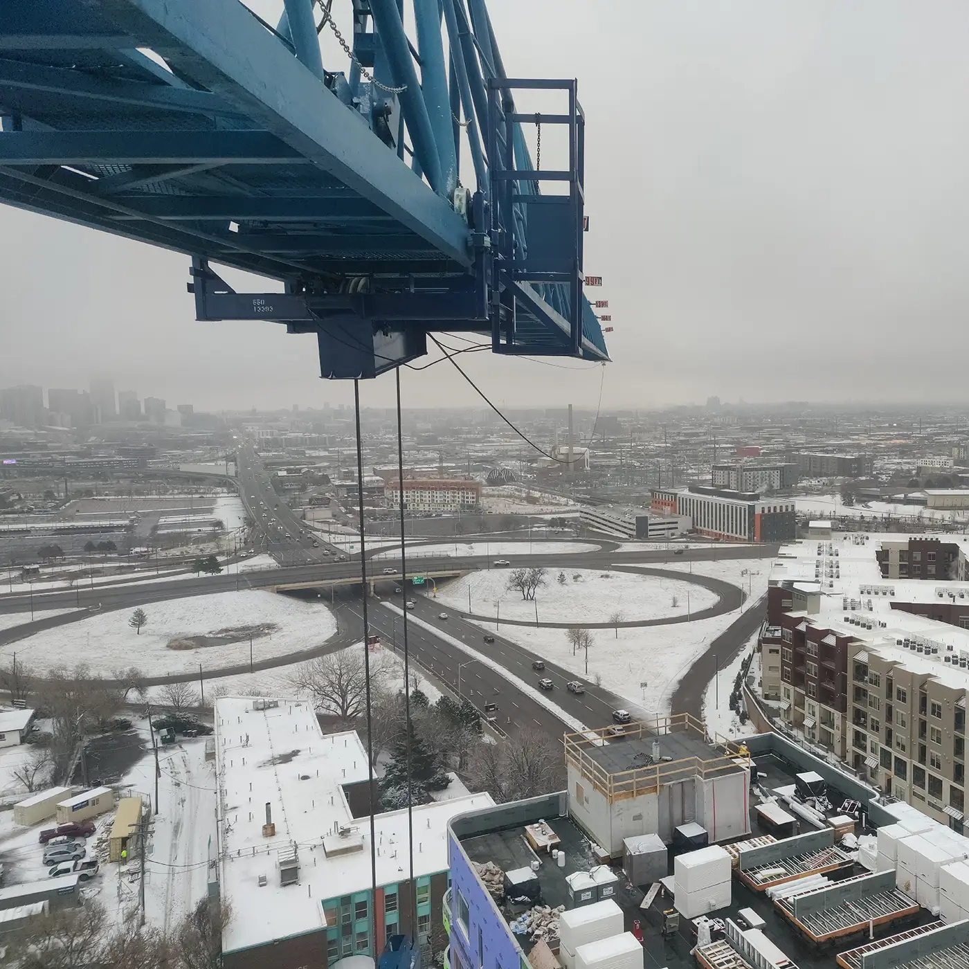 Aerial view from a telescopic crane cab overlooking city streets and buildings.