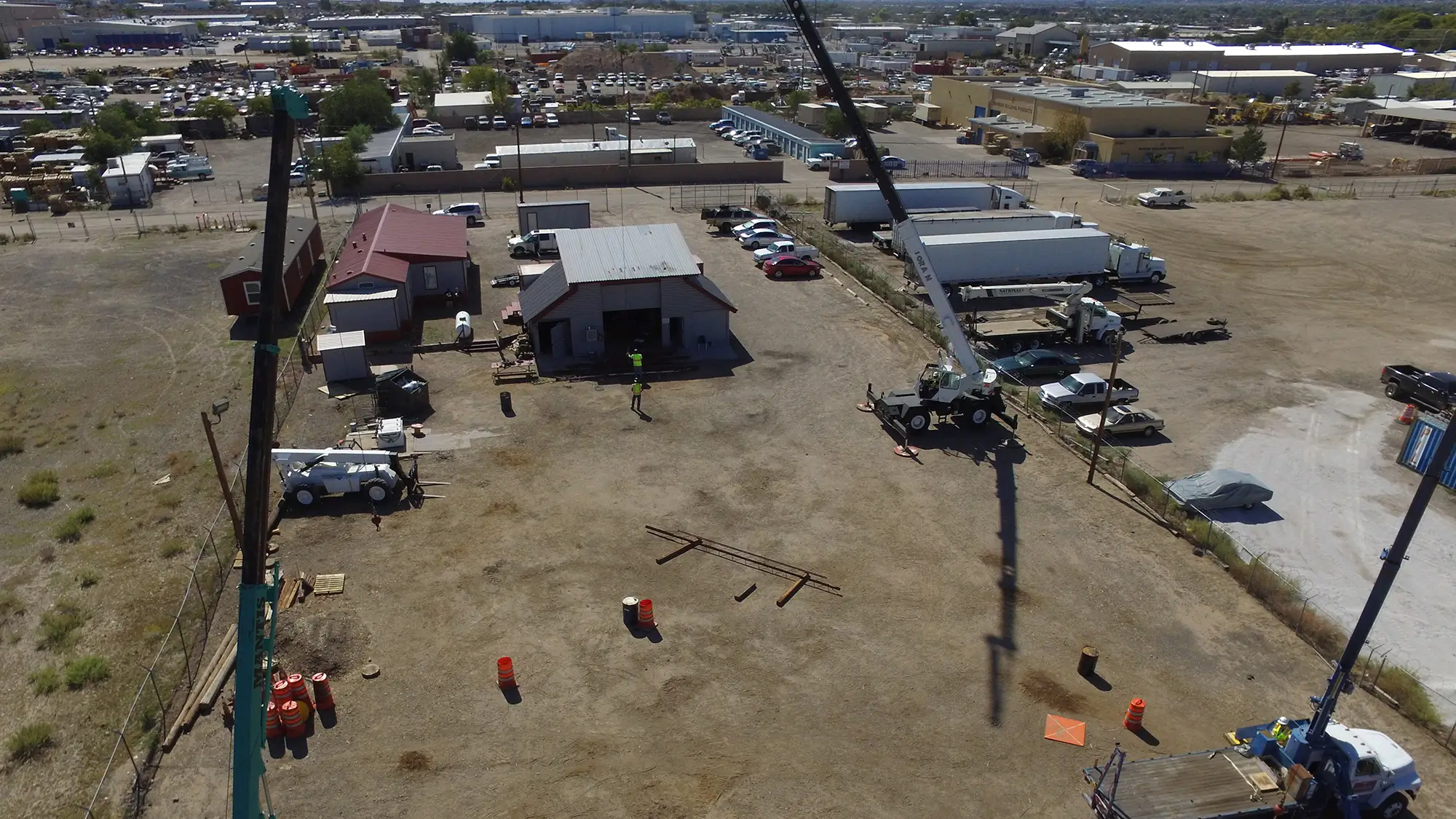 Overhead view of a training yard with two cranes and workers practicing lift director assembly and disassembly procedures.