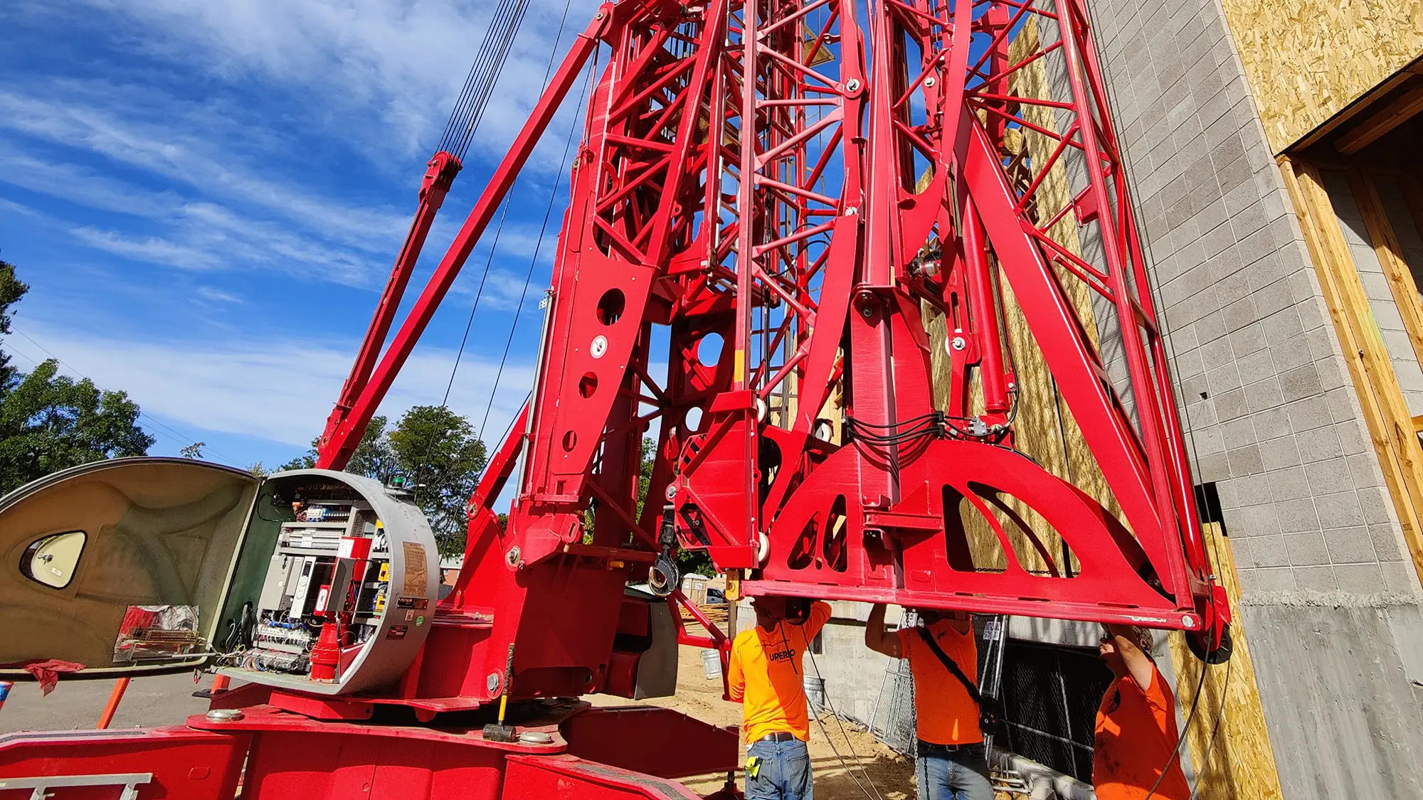 Workers in safety gear inspecting a large red mobile crane during overhead and mobile crane inspection training.