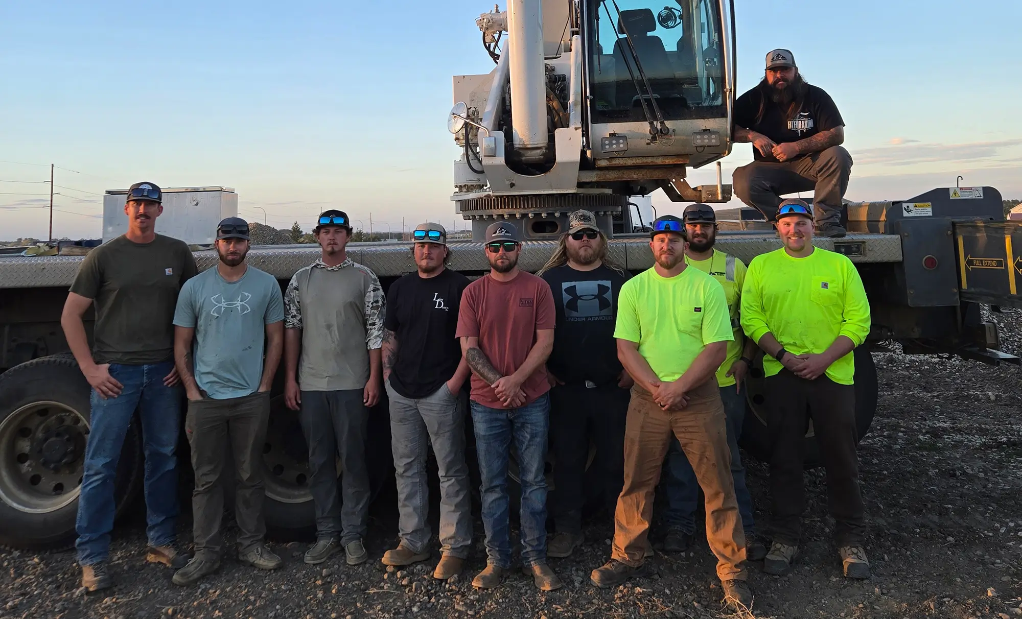 Group of crane operator trainees standing in front of a mobile crane during hands-on certification training.