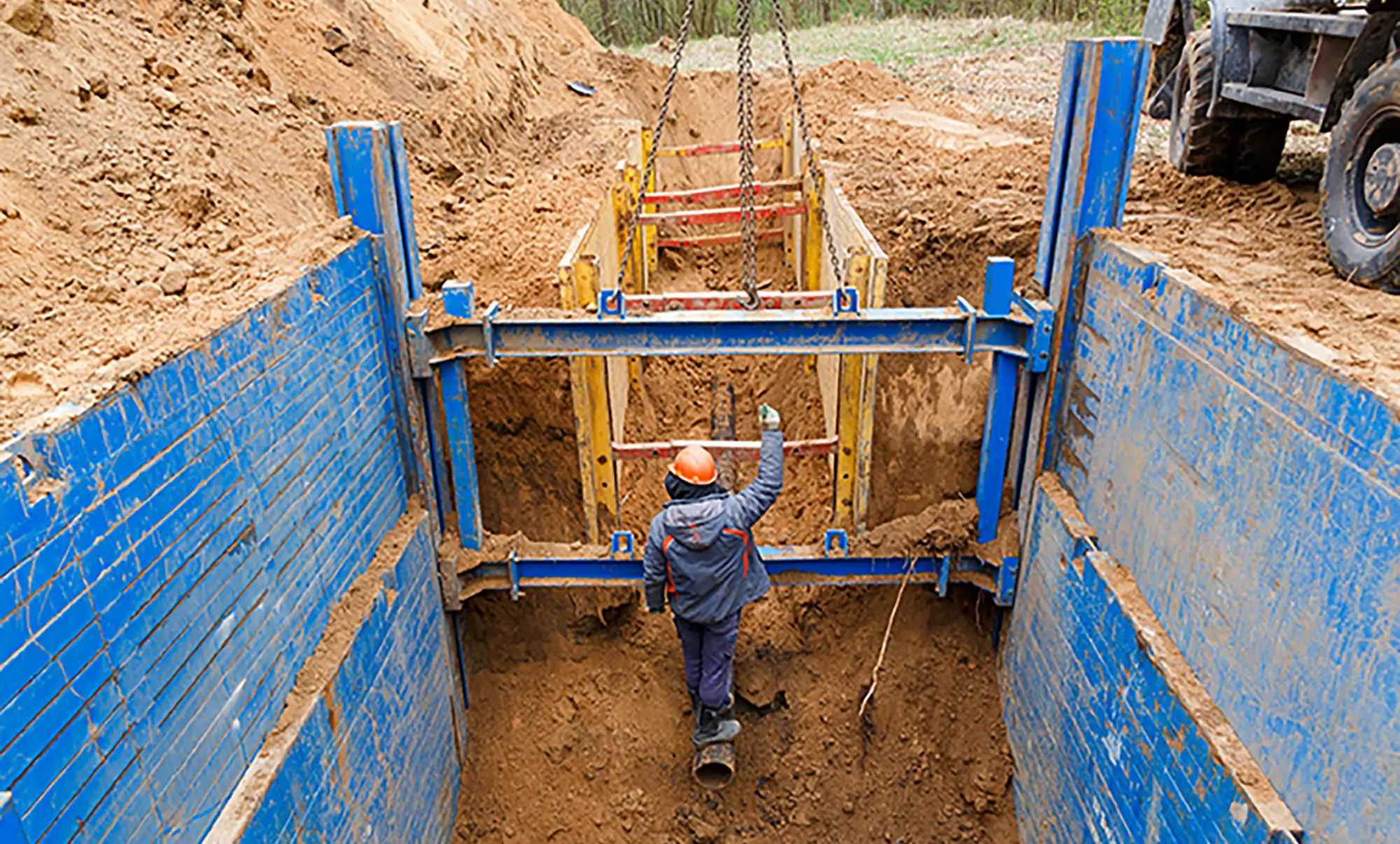 Construction worker inspecting trench shoring system during excavation safety and competent person training.