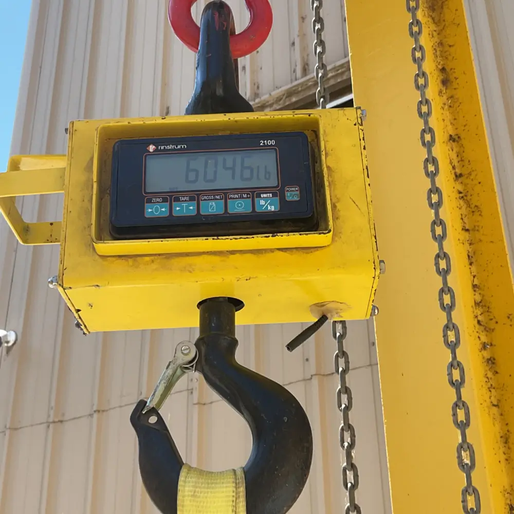 Crane hook and digital load scale showing 6046 pounds during lifting equipment inspection and testing.