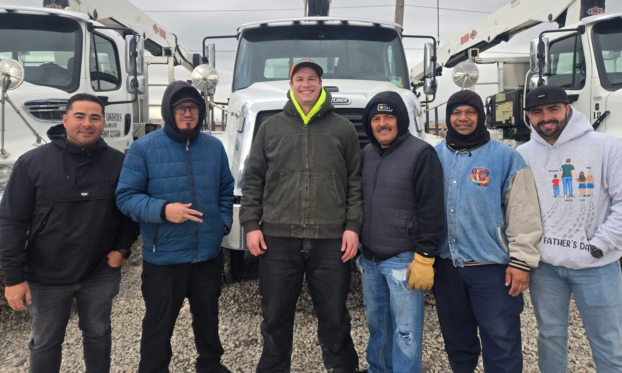 On-site crane training class group photo with students standing in front of boom trucks after hands-on instruction