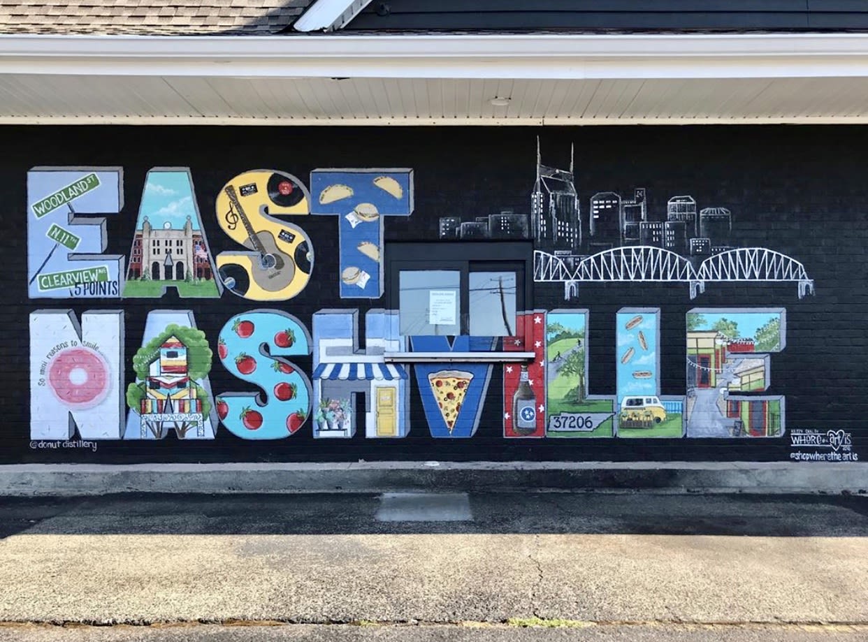 Colorful East Nashville mural featuring local landmarks, music symbols, food, and city skyline artwork painted on a brick wall