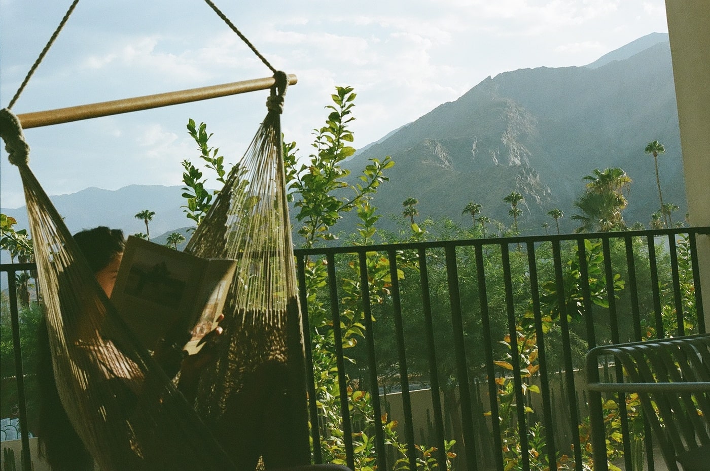 Guest reading in a hammock on a balcony with desert mountain views and palm trees